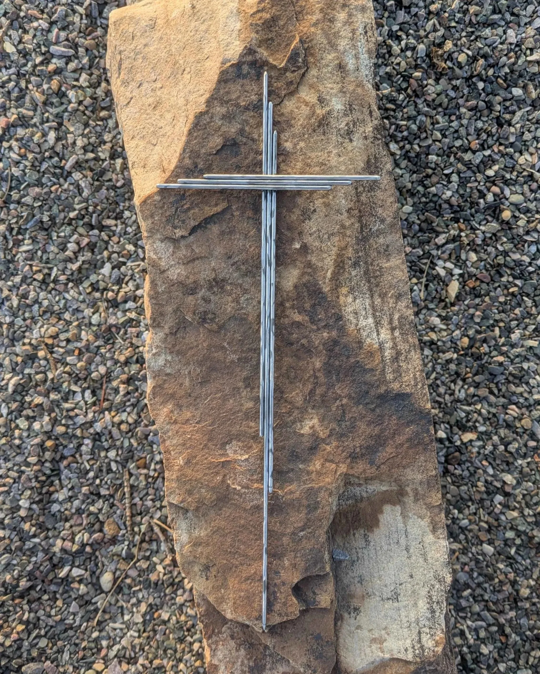 A metal art yard cross made from polished steel rods.