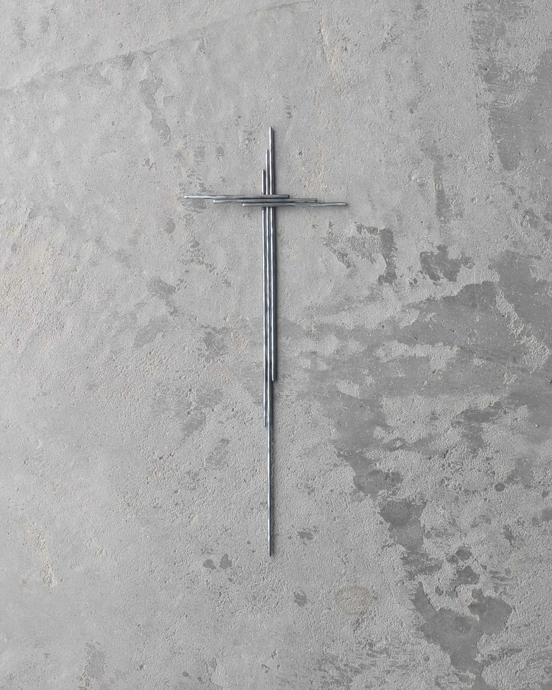 A metal art yard cross made from polished steel rods.