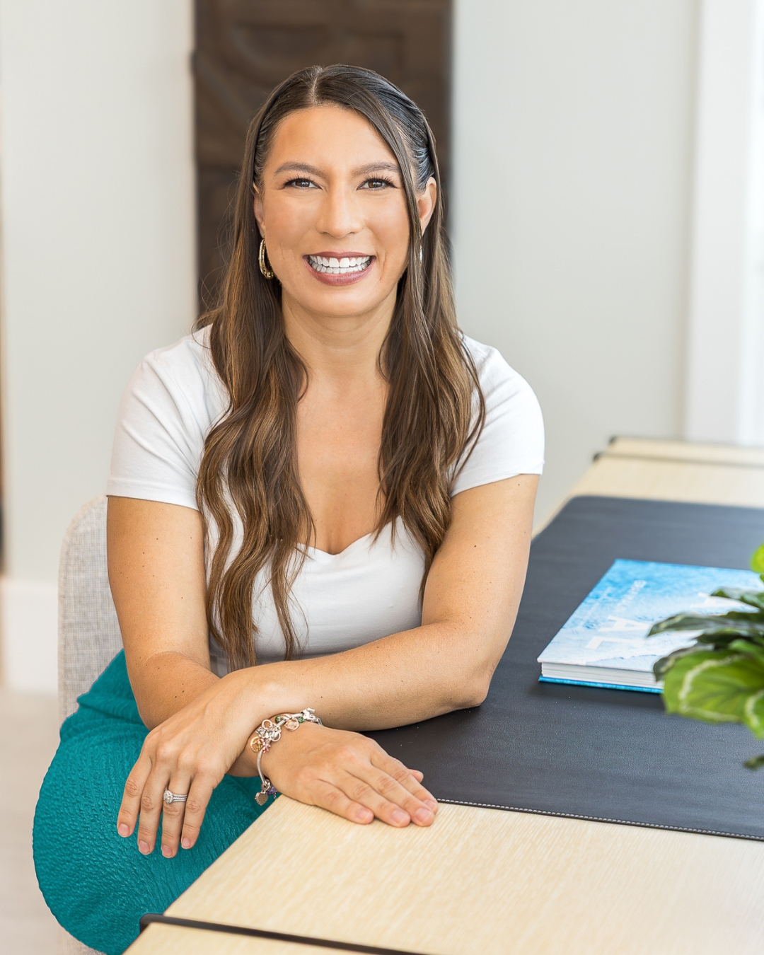 Tina Marie Gamble smiling at her desk in a white top and teal skirt