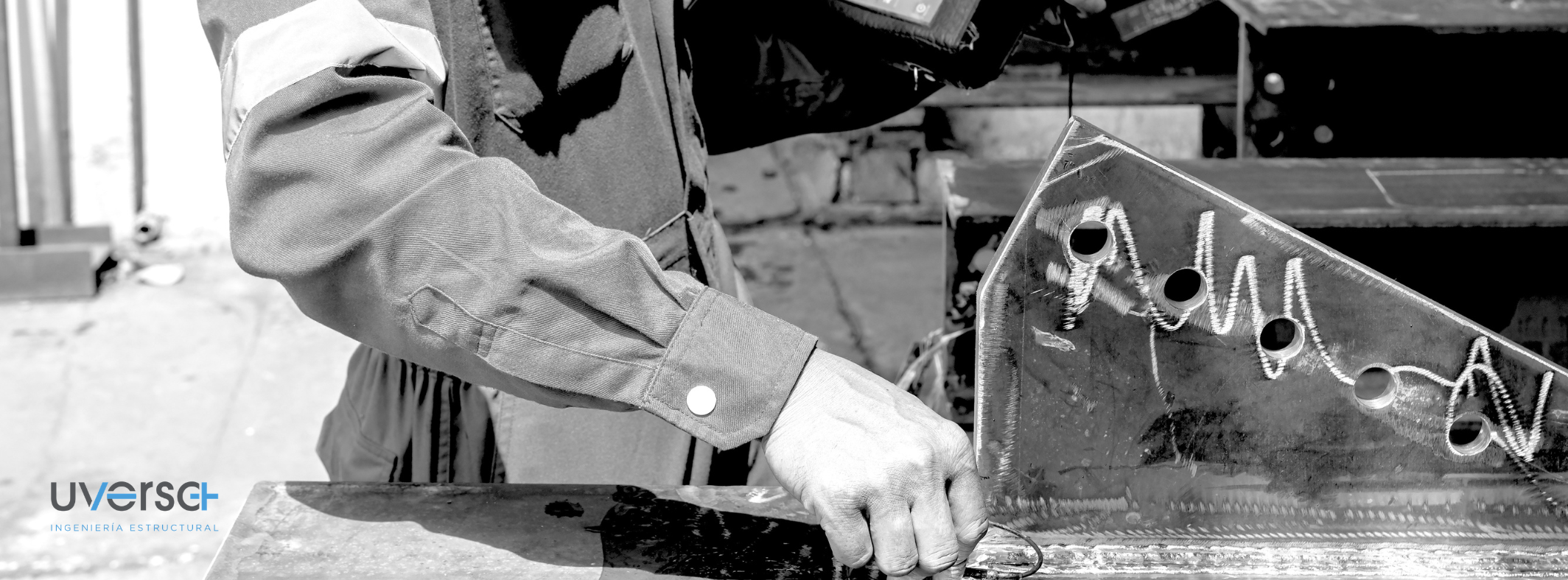 Persona soldando una estructura metálica en un entorno de construcción, con herramientas y materiales de trabajo visibles.