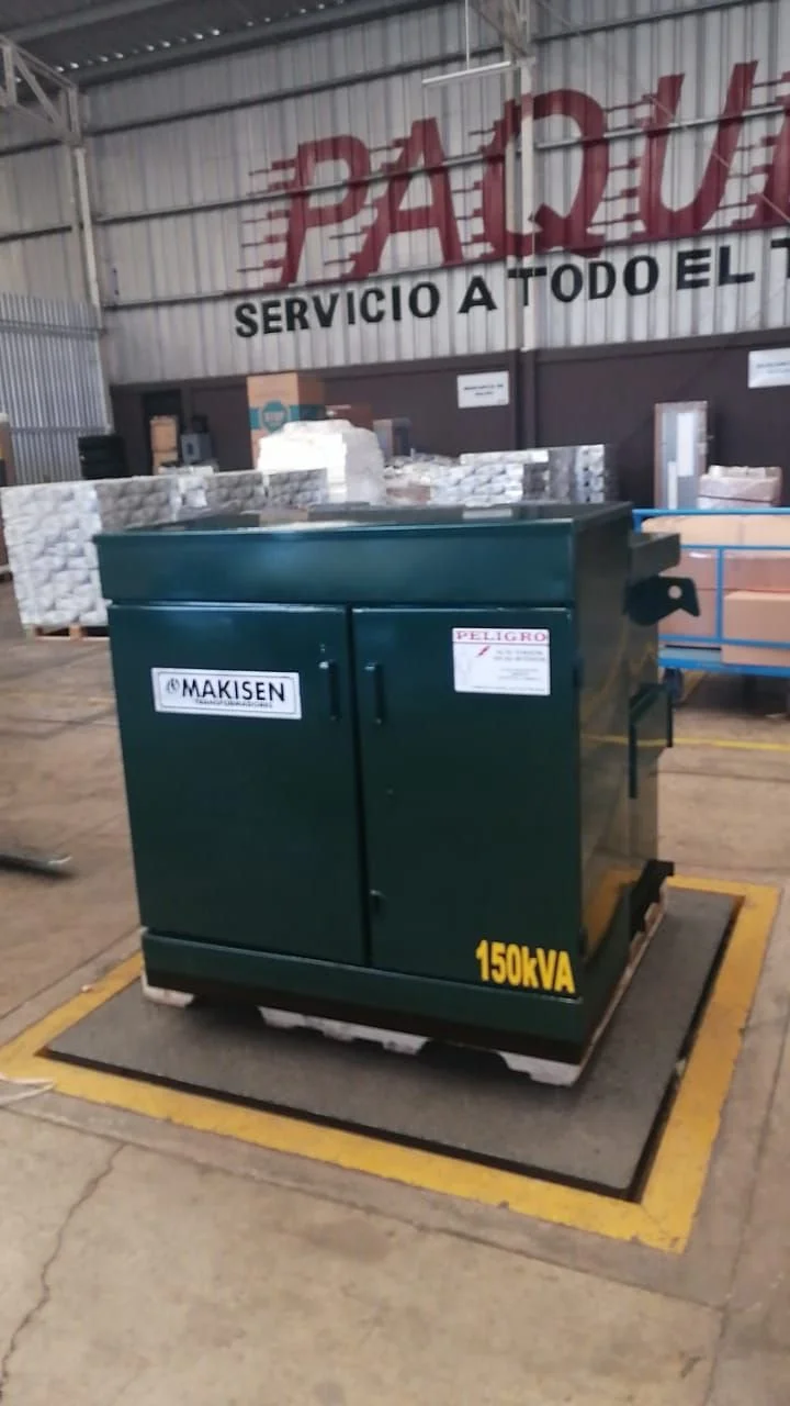 Un generador eléctrico verde en un almacén, con etiqueta que indica 150kVA y marca Makisen, colocado sobre una base de madera. En el fondo, palets con material y un cartel que dice "Palduz Servicio a Todo el".