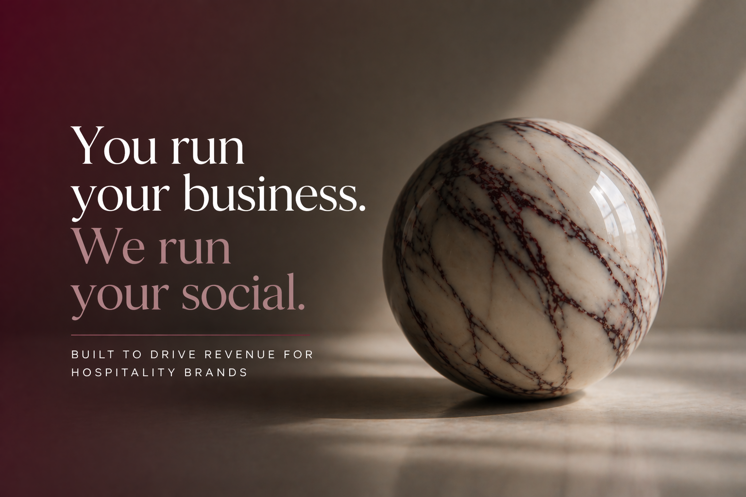 A marble sphere with red and white veins on a textured surface, illuminated by natural light with shadows cast on a neutral background, alongside text about business and social media management for hospitality brands.