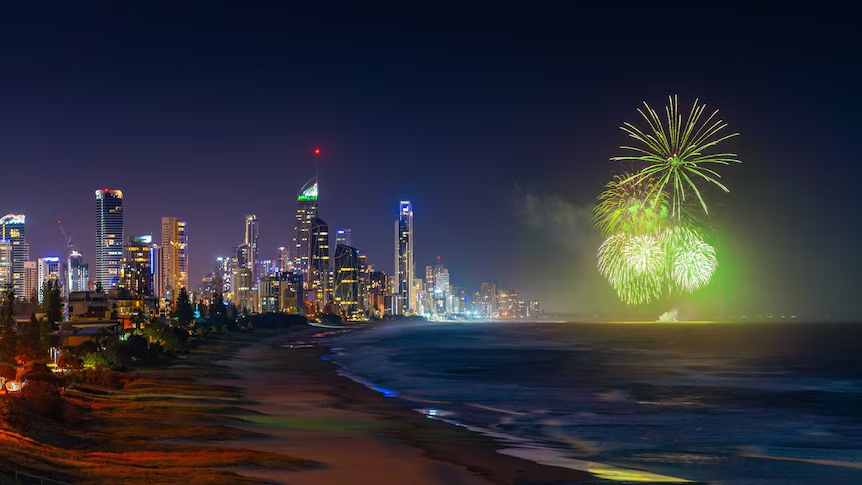 Nighttime view of a city skyline with fireworks over the water.