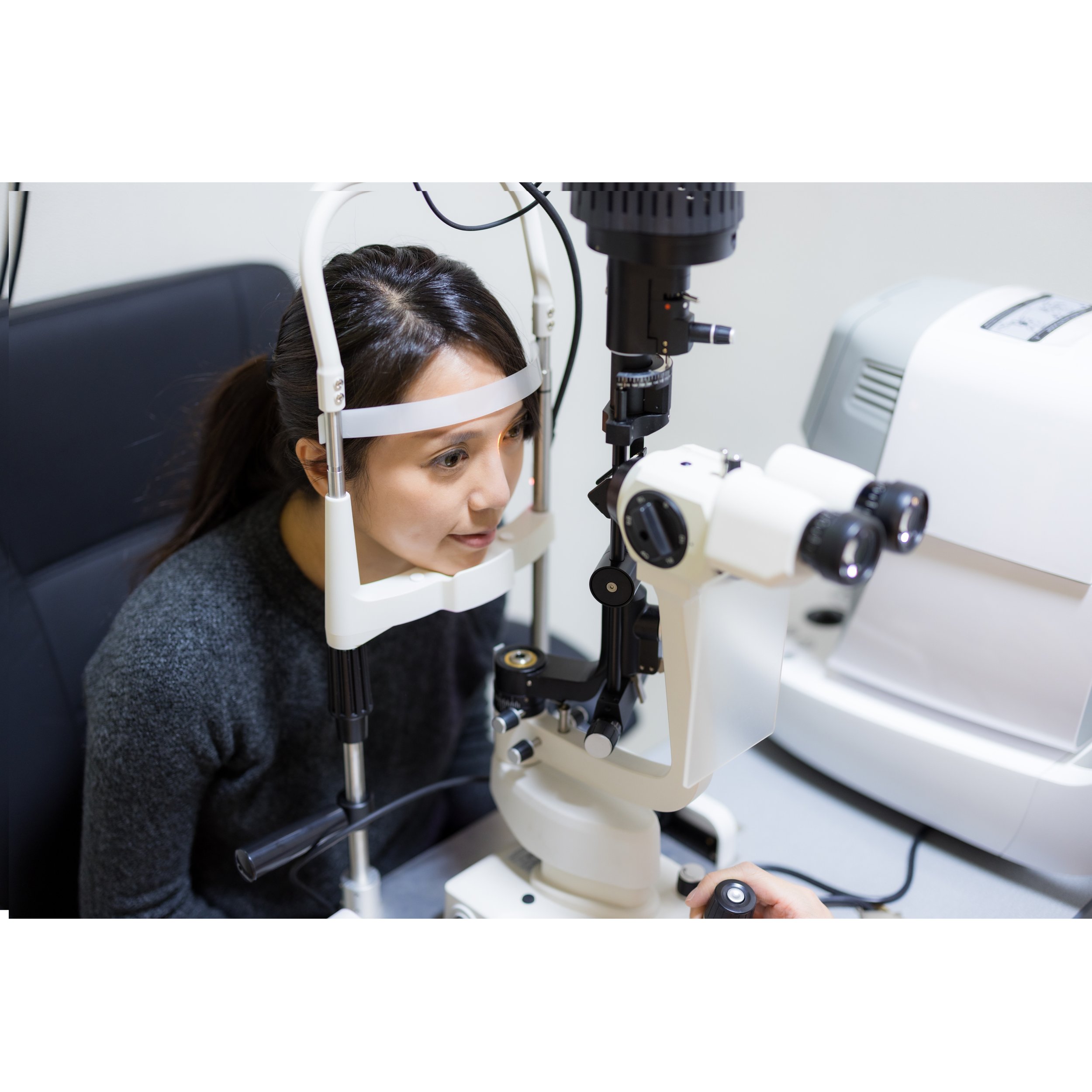 A woman undergoing an eye examination using a slit lamp microscope at an optometry clinic.