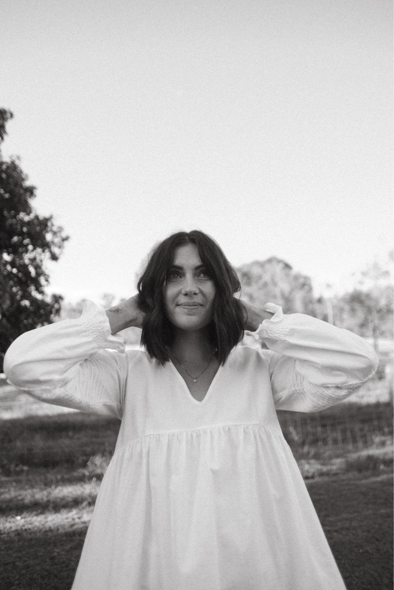 Rose Mills, brand identity designer, standing outdoors in a white dress, shot in black and white.