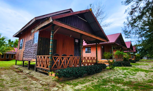 Multiple chalets with porches and red roofs in a rural setting with trees and grass.