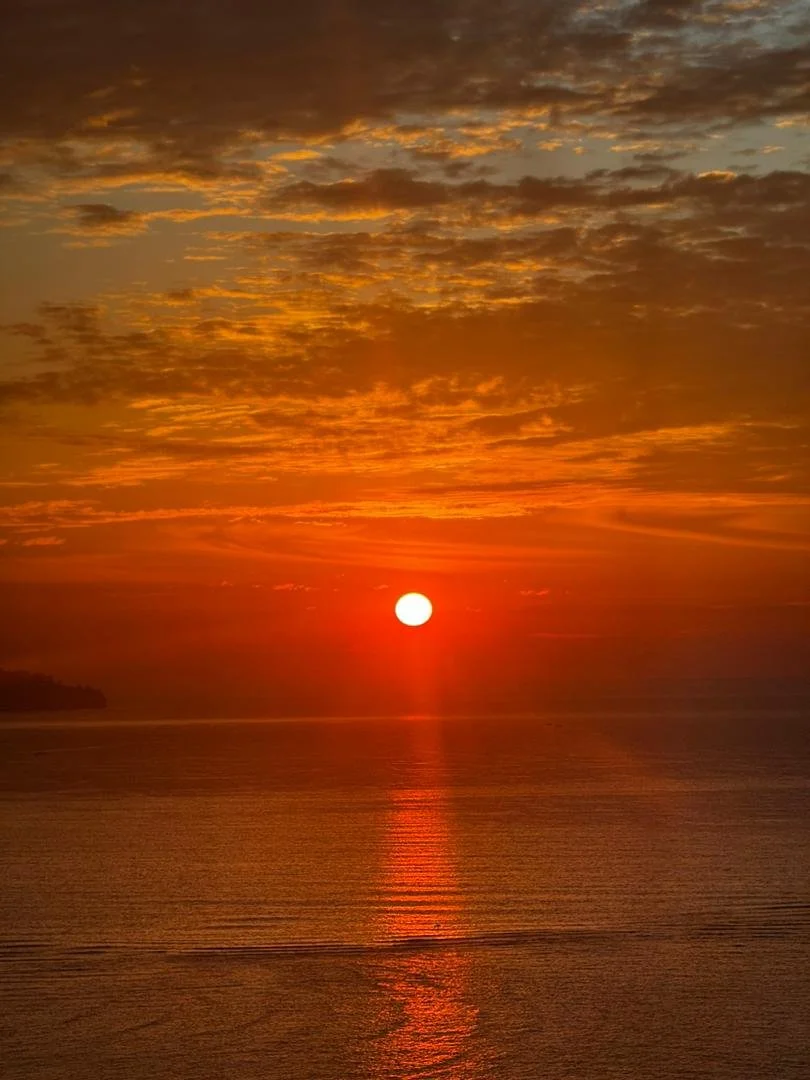 Sunset over the water with a golden sky and scattered clouds
