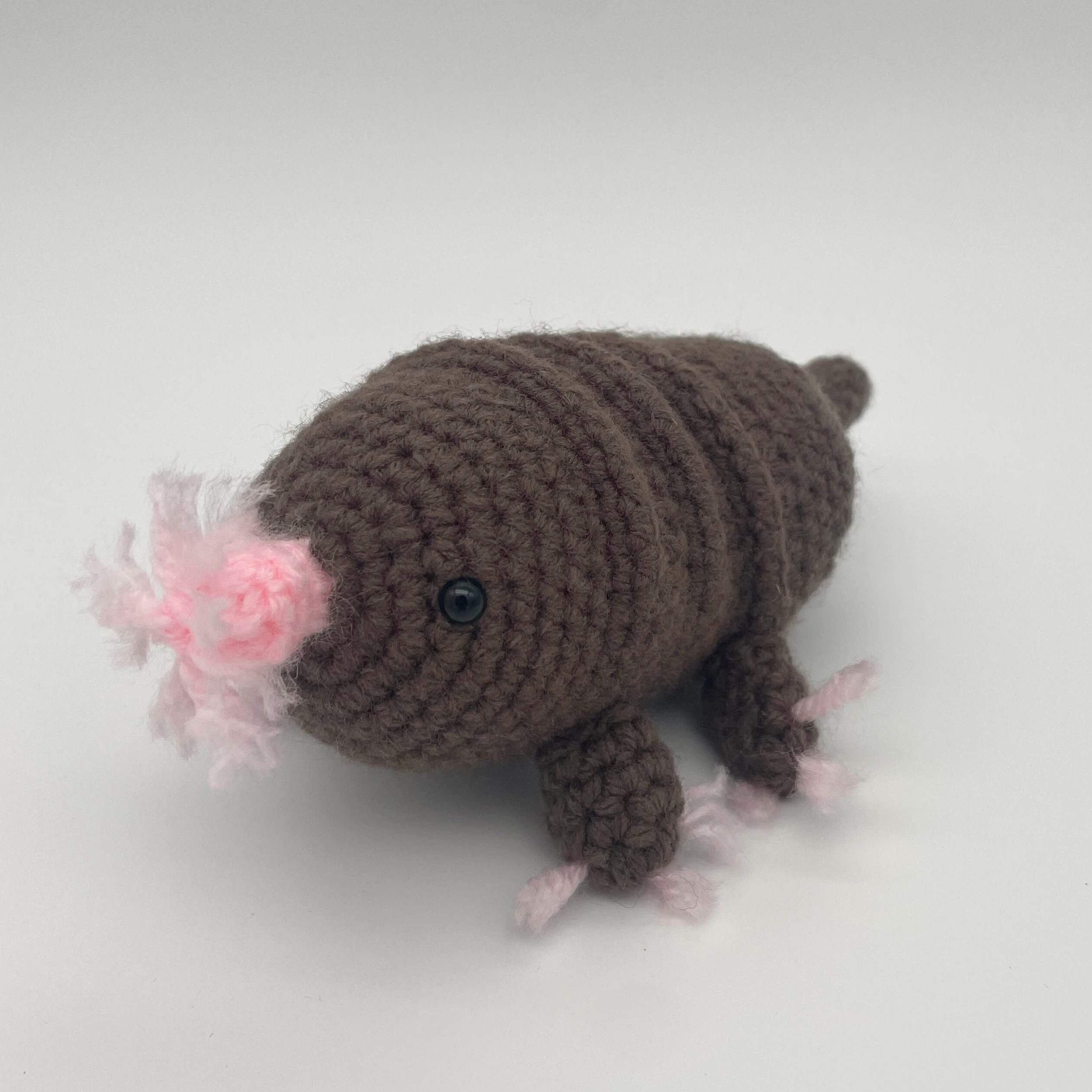 Brown crocheted star-nosed mole plush with a rounded segmented body, small black bead eyes, short legs, and a pink star-shaped nose, photographed against a light background.