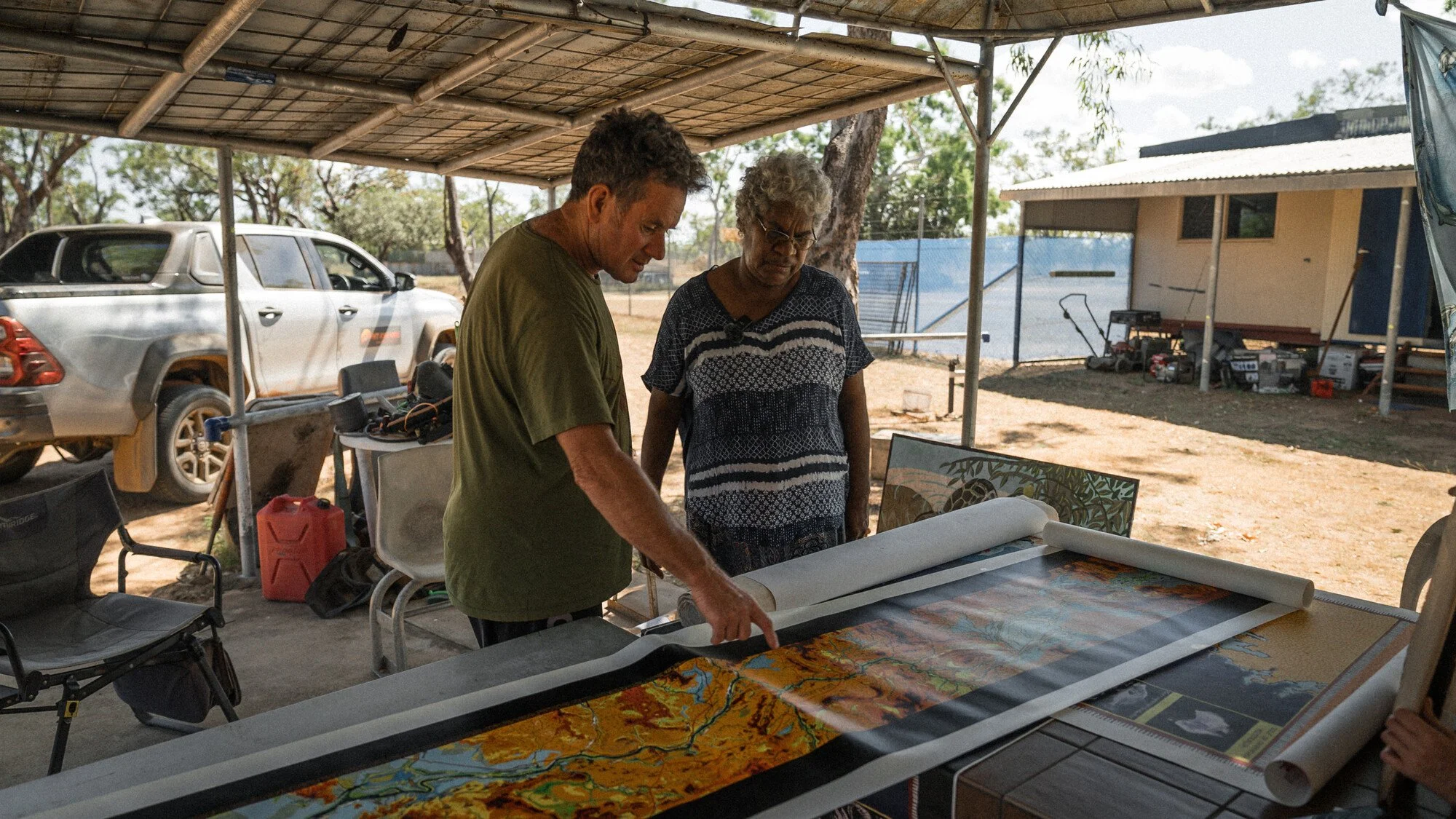 Indigenous and non-Indigenous people look over a large painted map of the Roper River