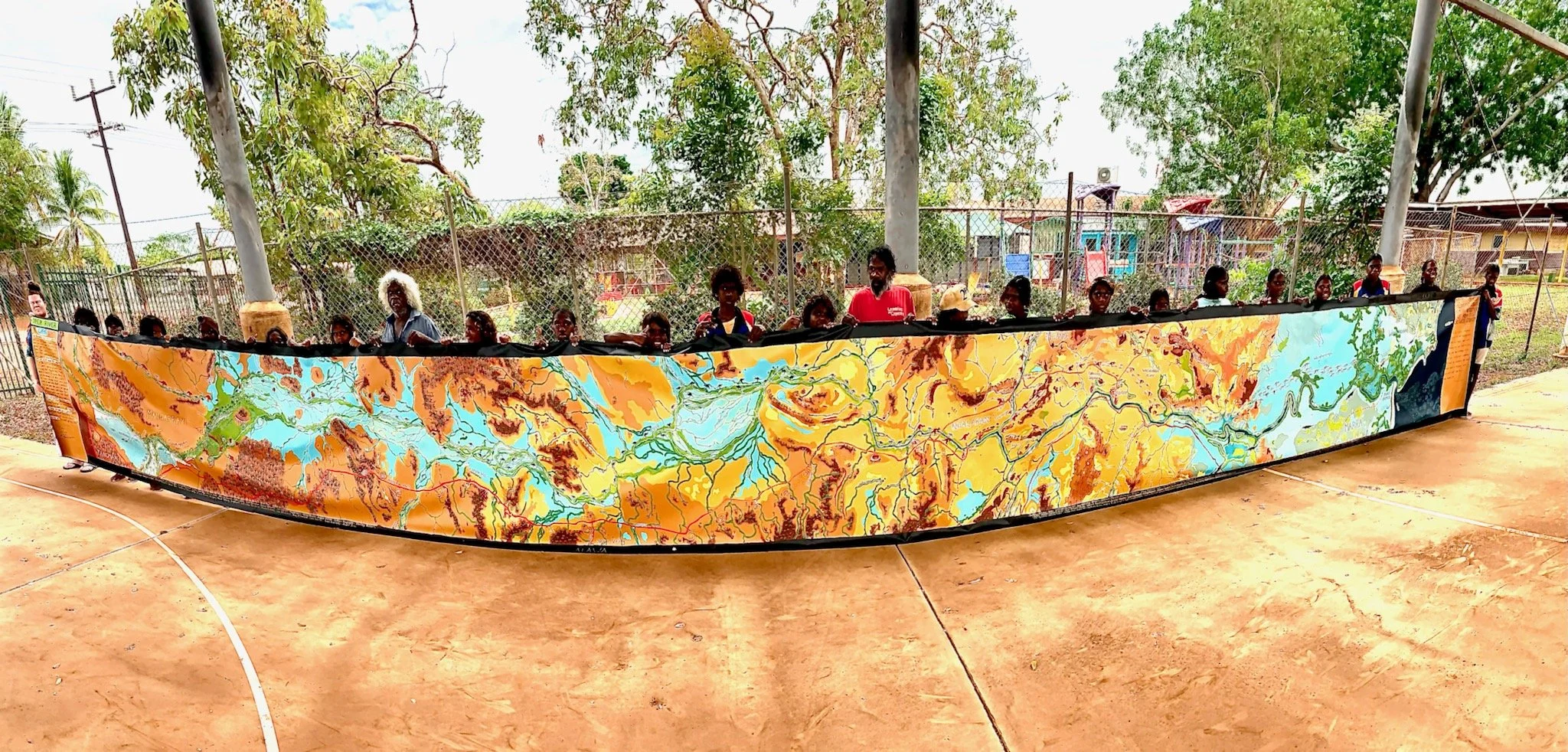 Children from a remote Indigenous school hold a large painted map of the Roper River