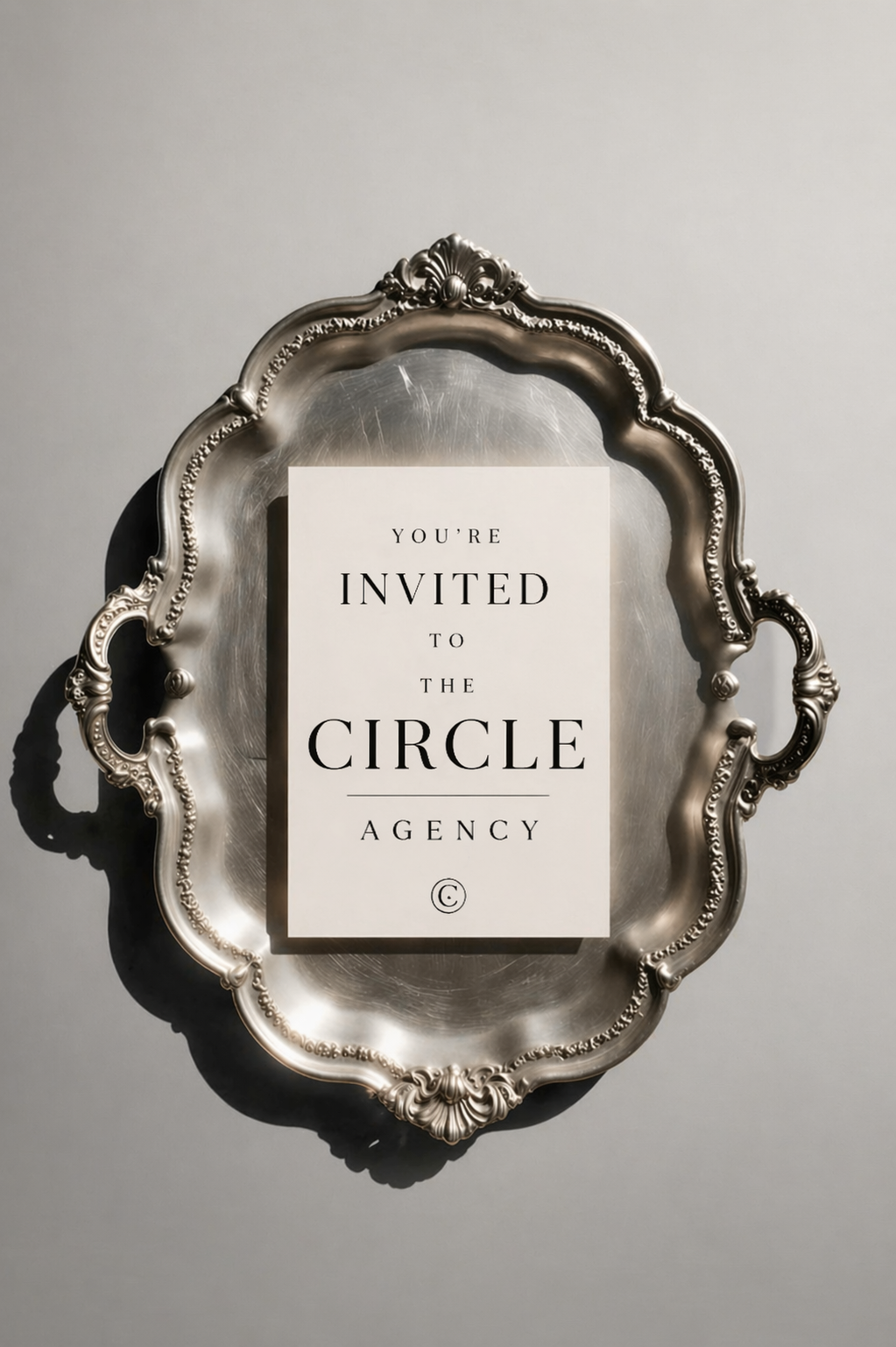 Invitation to the Circle Agency displayed on a white card, placed on a decorative silver tray with ornate edges.