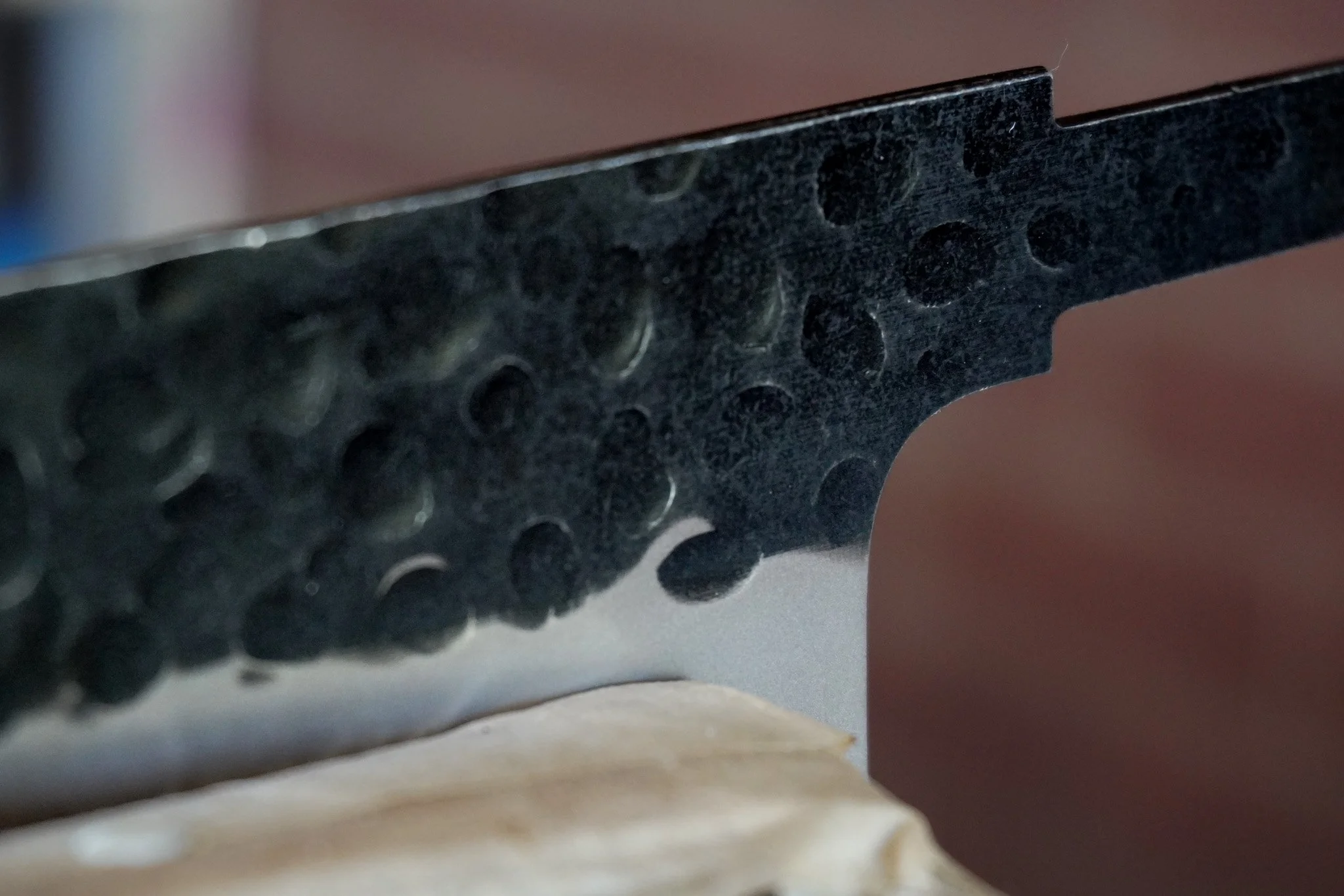 Close-up of a black object with a textured surface and circular indentations, partially covering a white surface underneath.