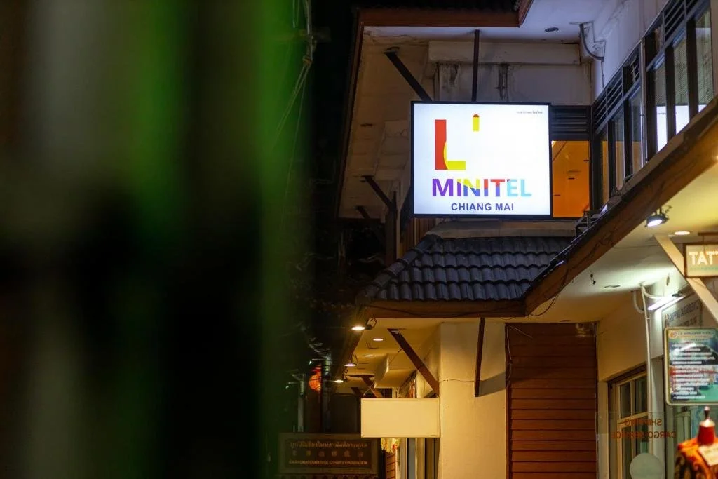 Nighttime view of a building with a brightly lit sign reading "MINITEL CHIANG MAI".