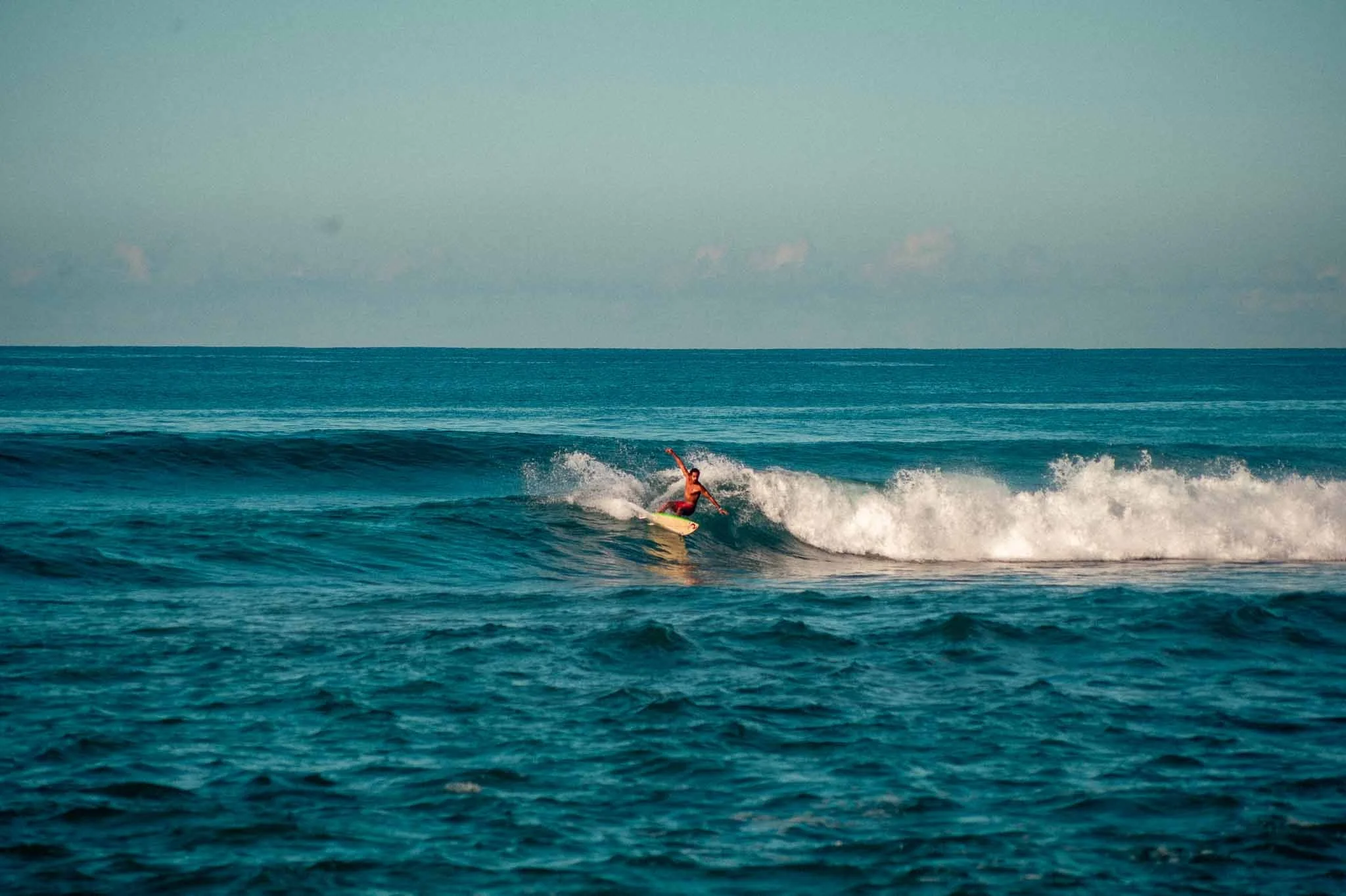 Lanka Surf House — Pitiduwa Village, Weligama — A surfer surfing on a wave at Rams (Midigama) in the ocean under a clear sky.