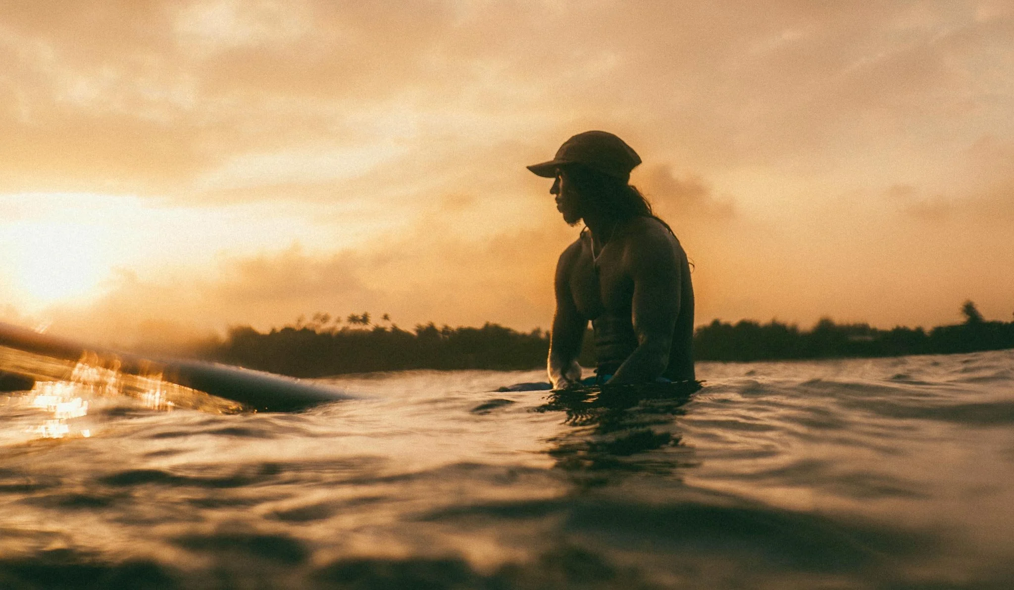 Lanka Surf House — Pitiduwa Village, Weligama — Anju our surf head coach and co-founder waiting for wave in Weligama bay during sunset, with a tropical shoreline in the background.