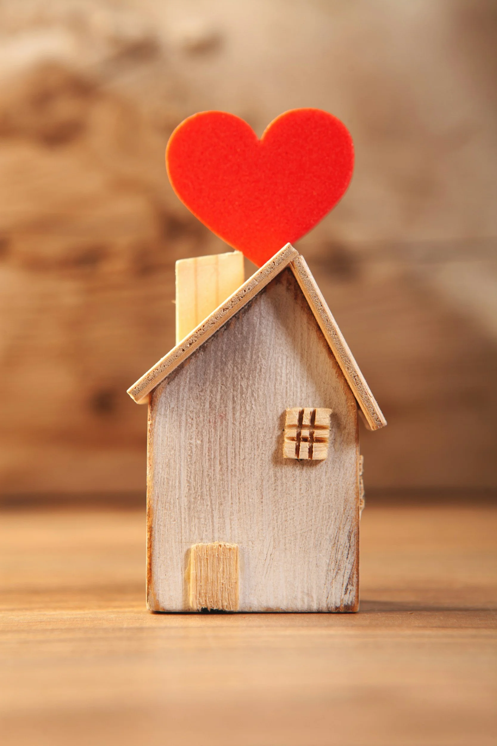 Small wooden house with a red heart decoration on top of the roof.