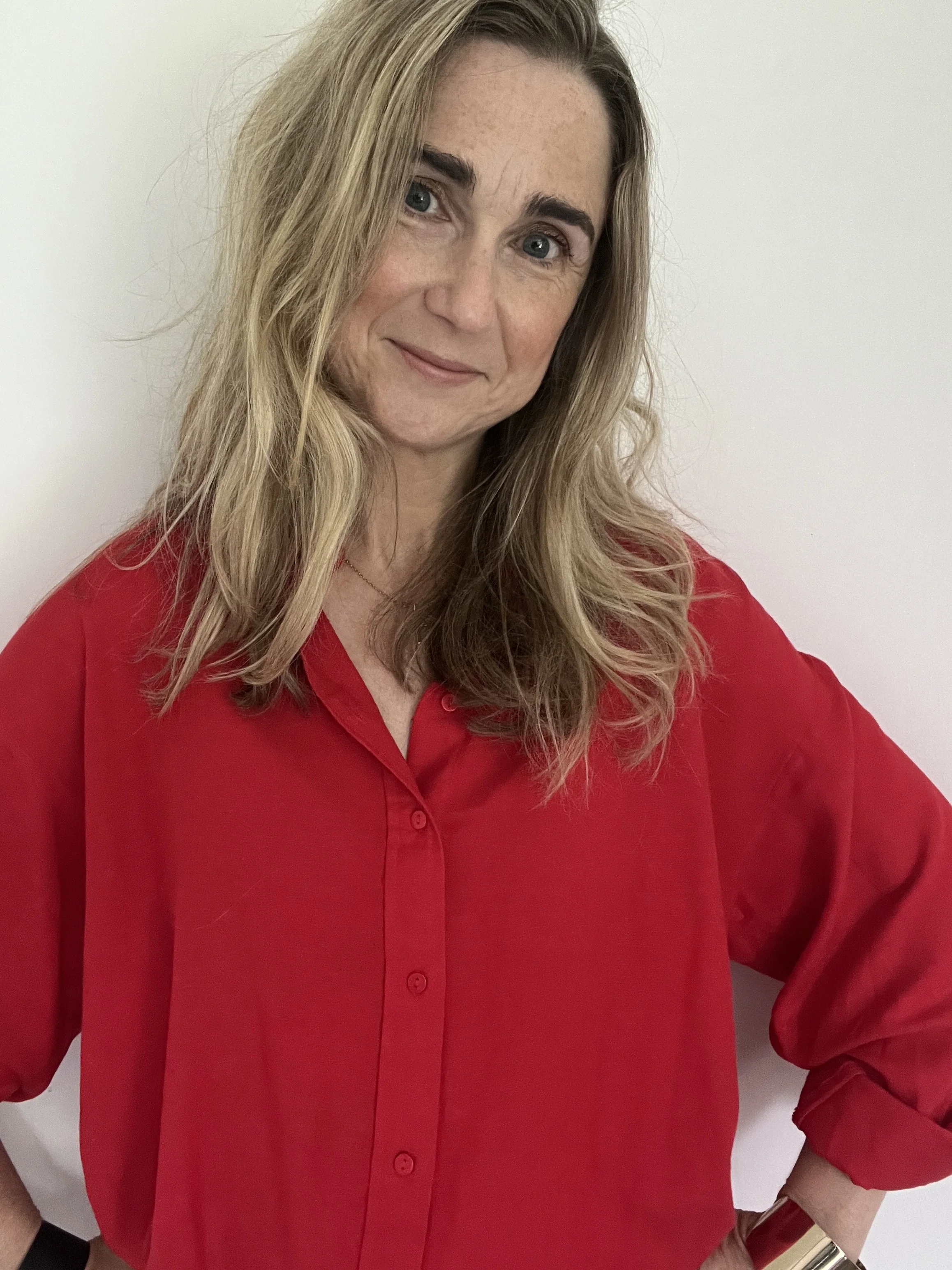 a blonde woman smiling dressed in a red shirt
