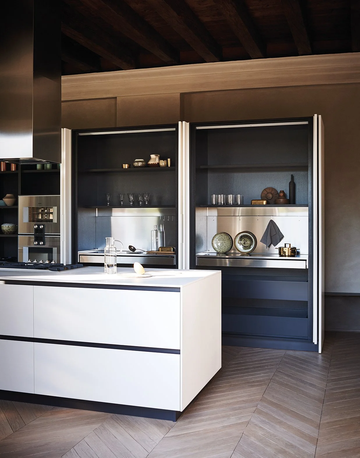 Moderne Küche mit schwarzem und weißem Schrank, offener Regale und Küchengeräten. Kücheninsel mit Wasserkrug und Dekorationen auf dem Tisch.
