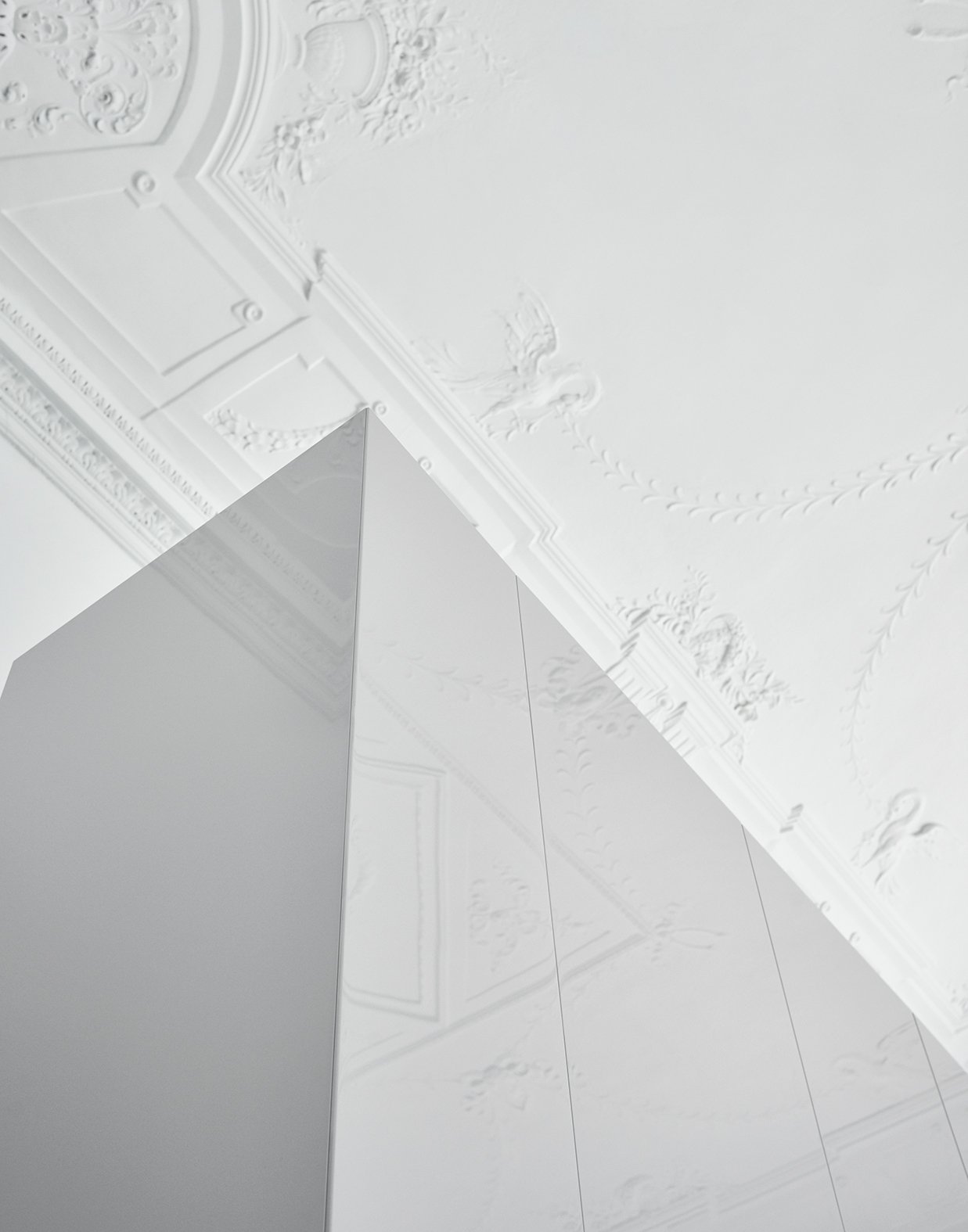 Weiße, moderne Wand und Decke mit dekorativen Stuckelementen in einem Raum, Blick nach oben.