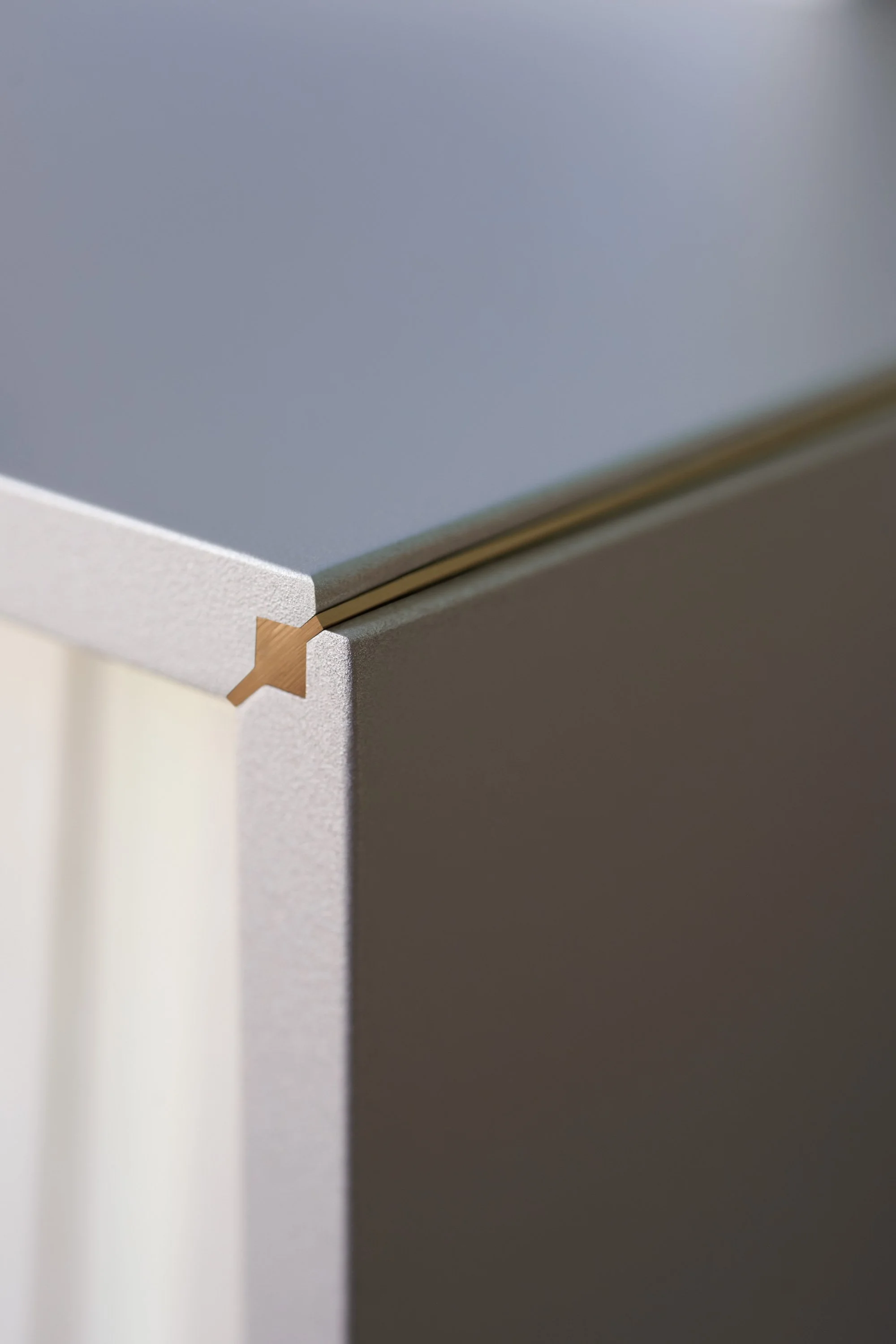 Nahaufnahme eines Eckenstücks eines Möbelstücks mit weißer Oberfläche und Holzdetails, vermutlich ein Schreibtisch oder eine Kommode.