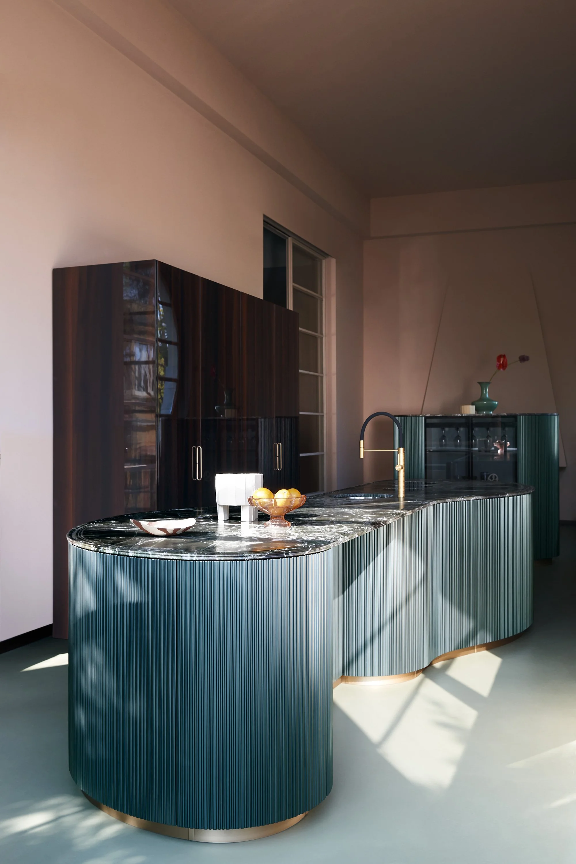 Moderne Küchentheke mit dunklem, geripptem, blaugrauem Design, goldener Wasserhahn, dekorativer Früchte-Schale und schwarzen Küchenmöbeln im Hintergrund.