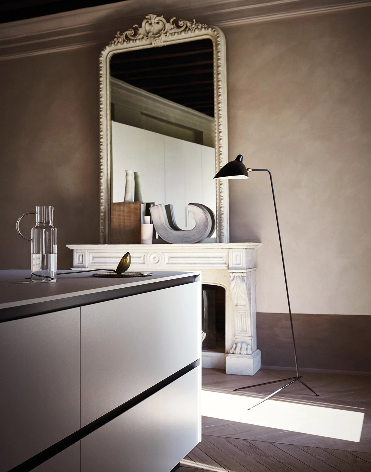 Innenaufnahme eines modernen Raumes mit antikem Kamin, einem großen Spiegel und einem stilvollen Stehlamp, dekoriert mit Vasen, einer Skulptur und Kerzen. Das Design kombiniert klassische und moderne Elemente.