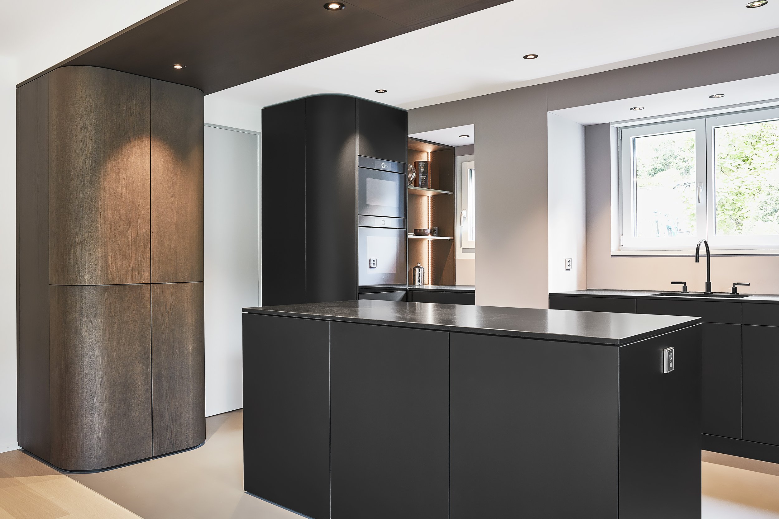 Moderne schwarze und hölzerne Küchenschränke mit Fenster und Wasserhahn