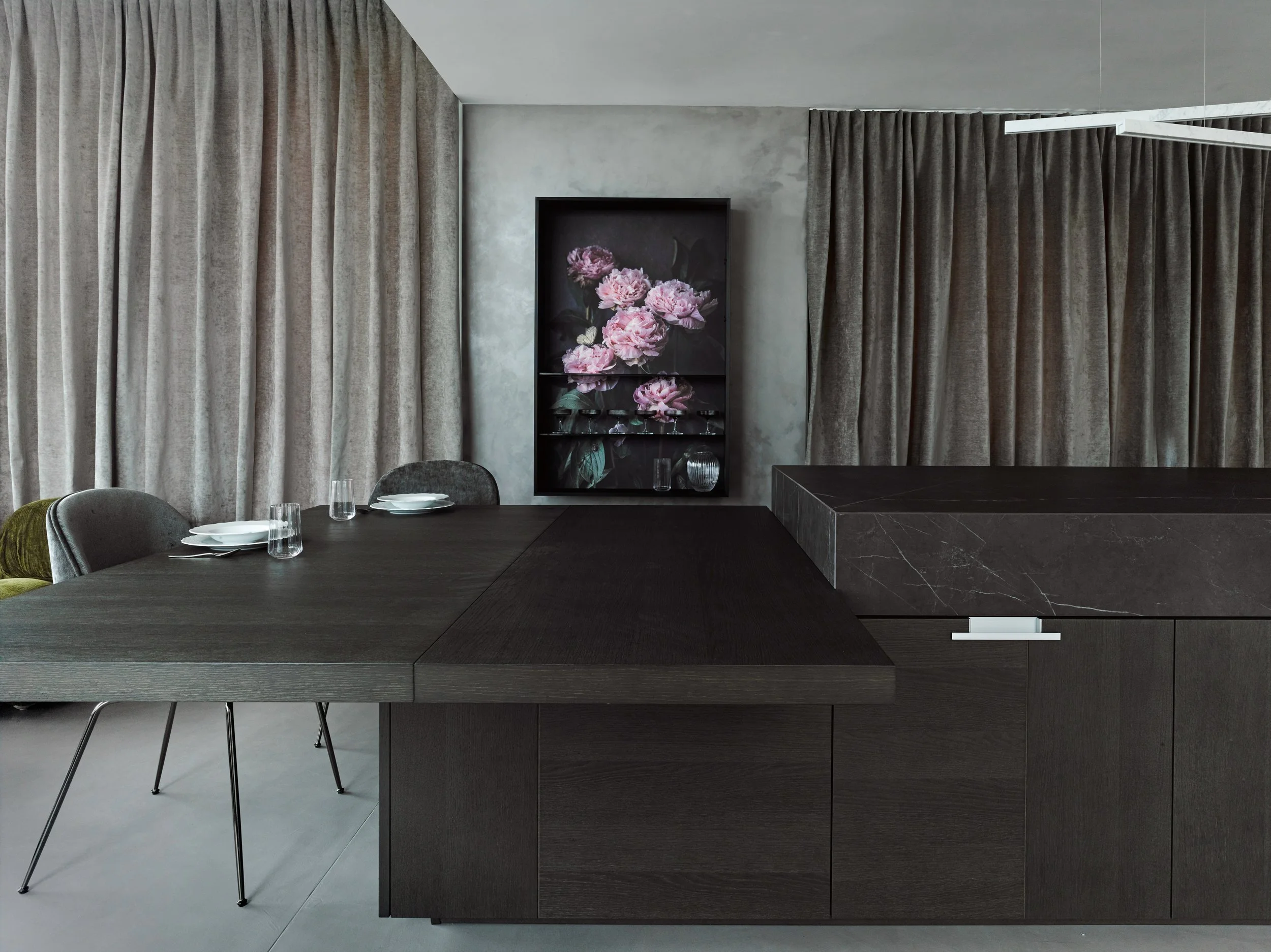 Modernes Esszimmer mit dunkelbraunem Tisch, grauen Stühlen, grauen Vorhängen, einem schwarzen Regal mit Flamingo-Bild, und dunklem MÖbel aus Marmor
