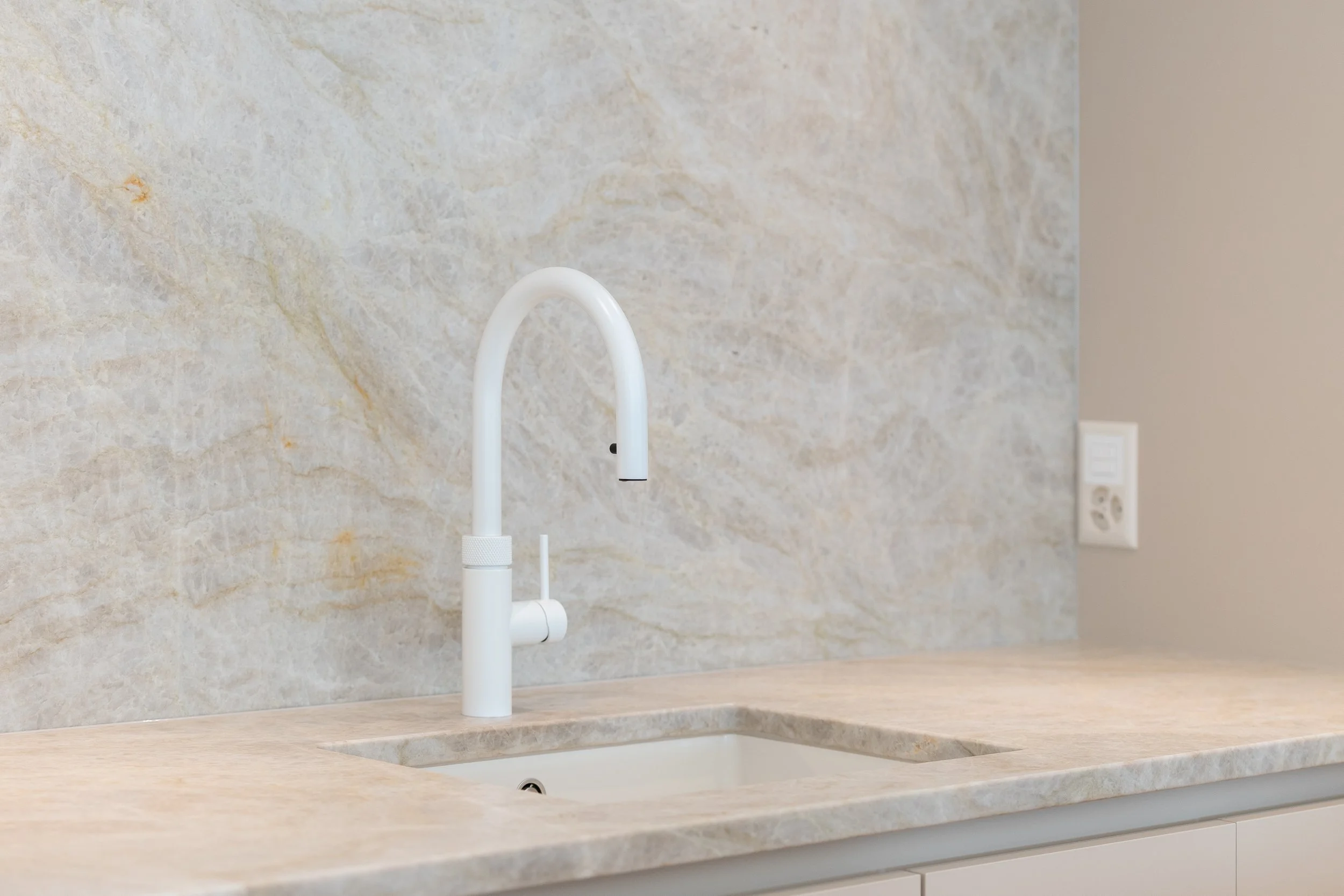 Weiße Küchenarmatur über einem eingebauten Waschbecken in einer modernen Küche.