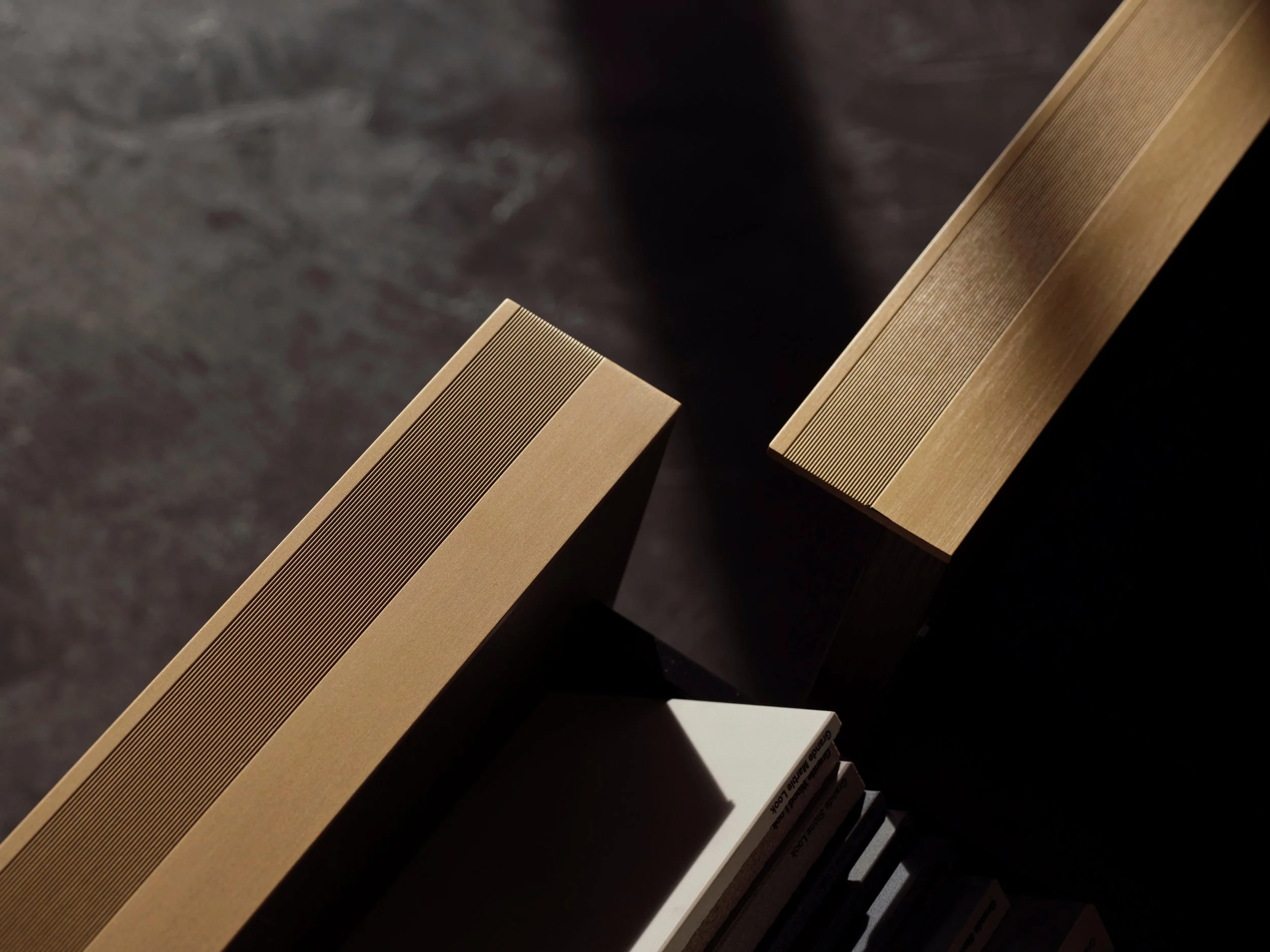 Nahaufnahme von mehreren Buchrücken im Regal, hauptsächlich aus Holz und Papier, mit einem dunklen Hintergrund.