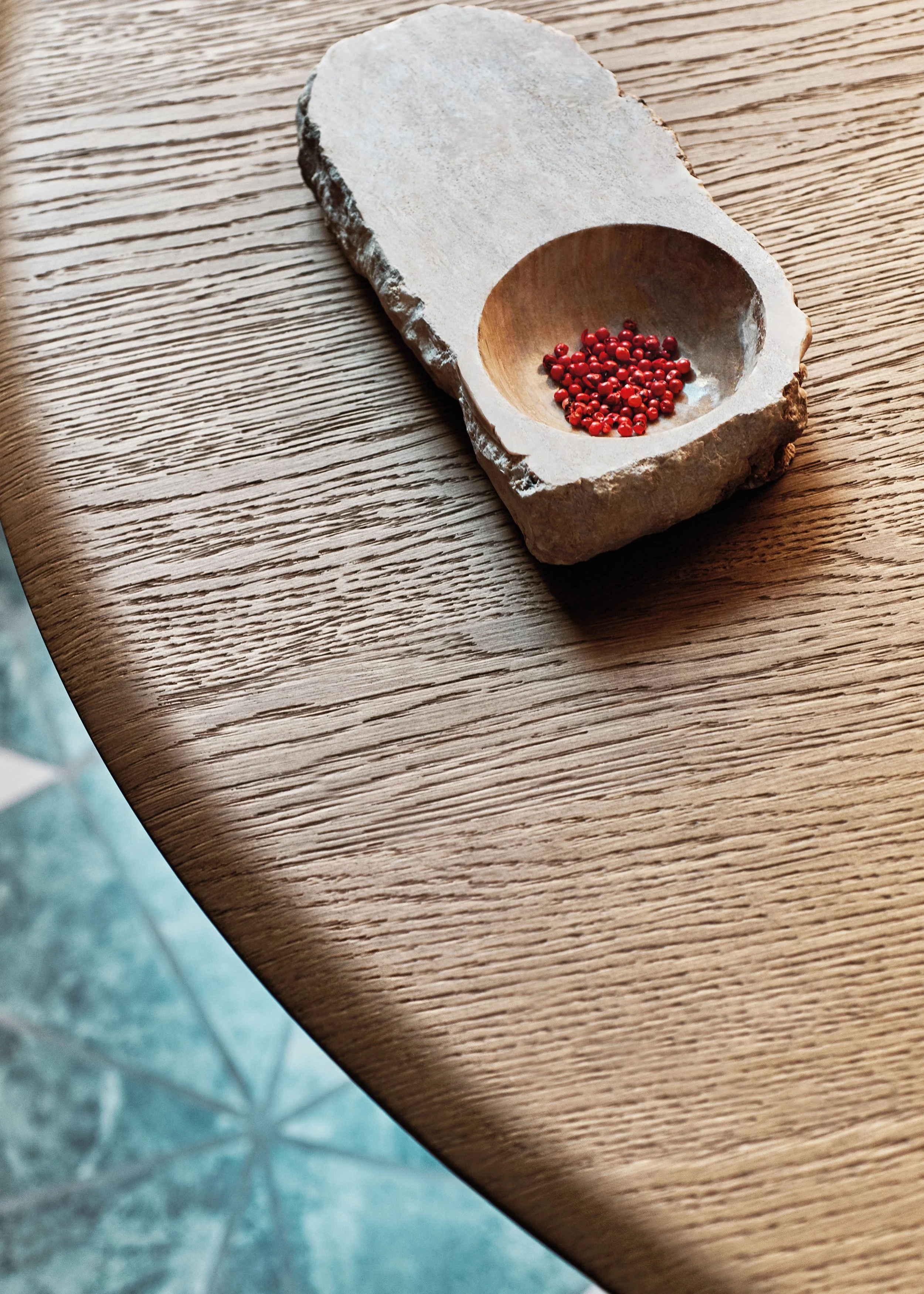 Ein Holztisch mit einer kleinen Steinhalterung, die rote Pfefferkörner enthält.