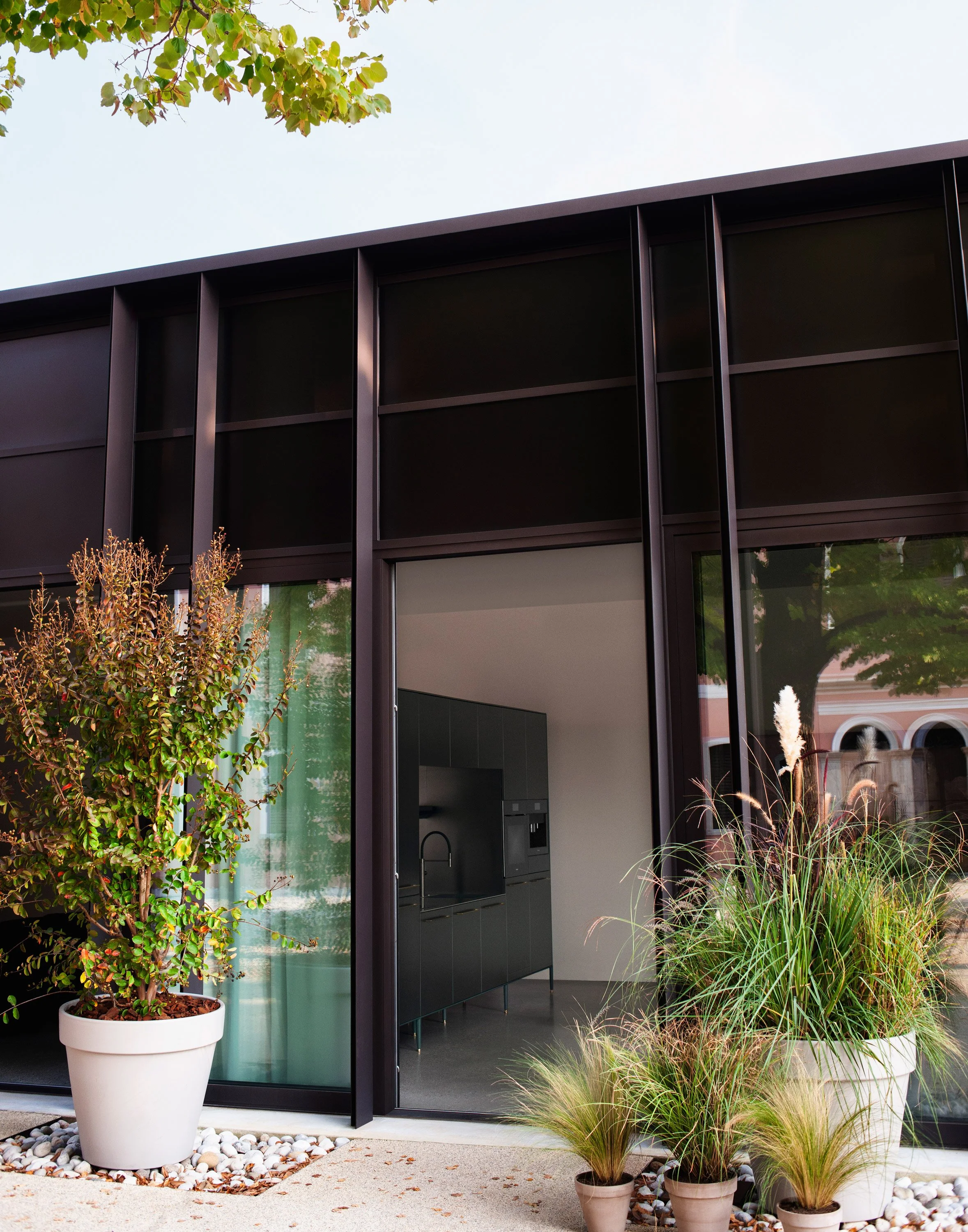 Ein moderner Bürobau mit großen Fenstern und umgeben von Pflanzen im Garten.