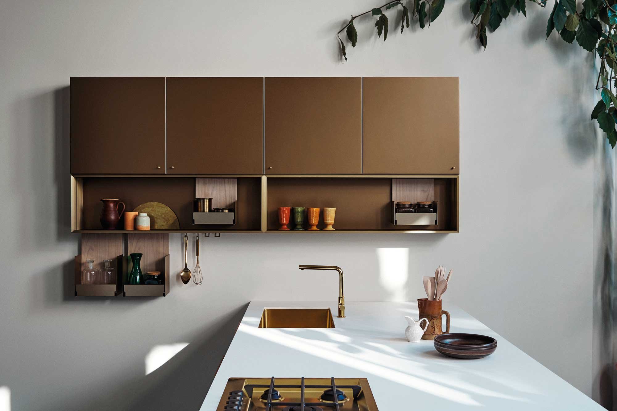 Moderne Küche mit brauner Wandregal, weißen Arbeitsfläche, Goldarmatur, Topf, Keramikfiguren, bunten Bechern, und grünen und braunen Dekorationen.