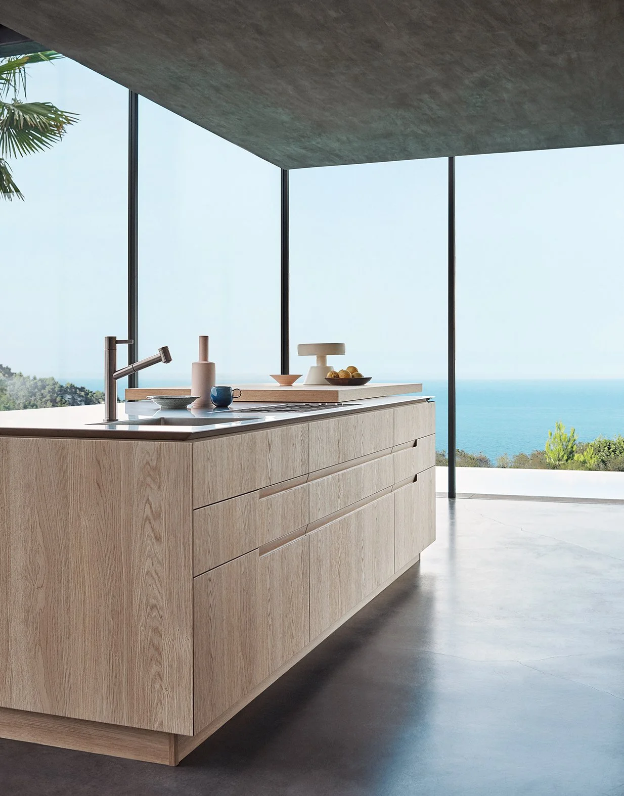 Moderne Küchenschrein mit Blick auf das Meer im Hintergrund, natürlicher Holzküchenblock, Wasserhahn, Geschirr, Obst und Dekorationsartikel