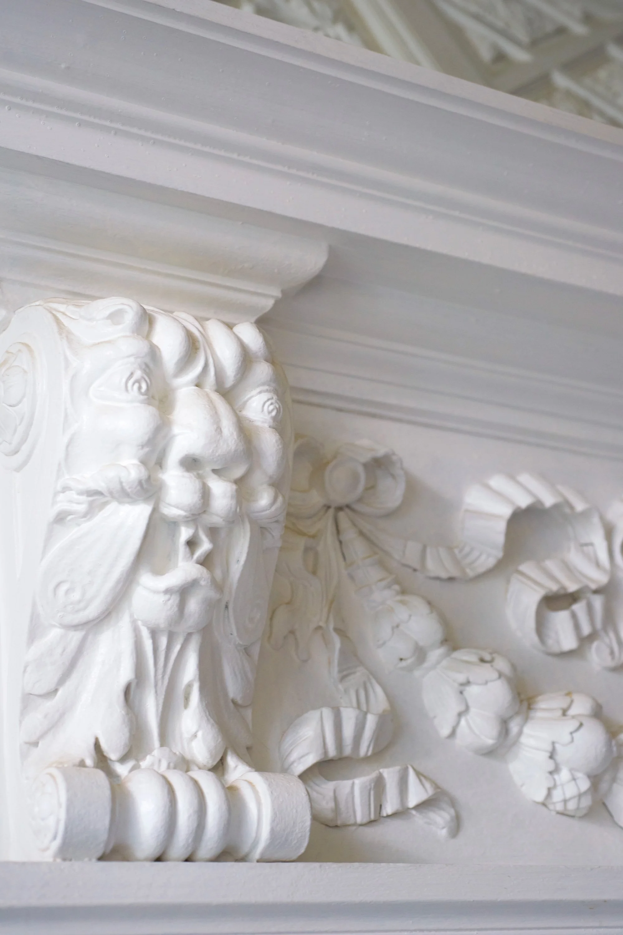 Detailaufnahme einer weißen, kunstvollen, barocken Holzverzierung.
