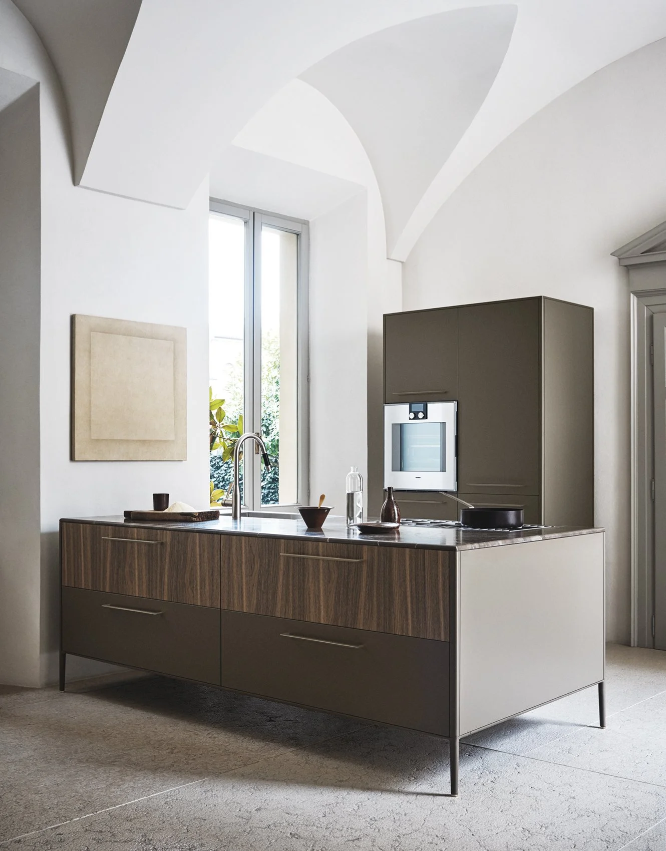 Moderne Küche mit grauem Schrank, Backofen, Waschbecken, Fenster, Pflanzen und minimalistischer Dekoration.
