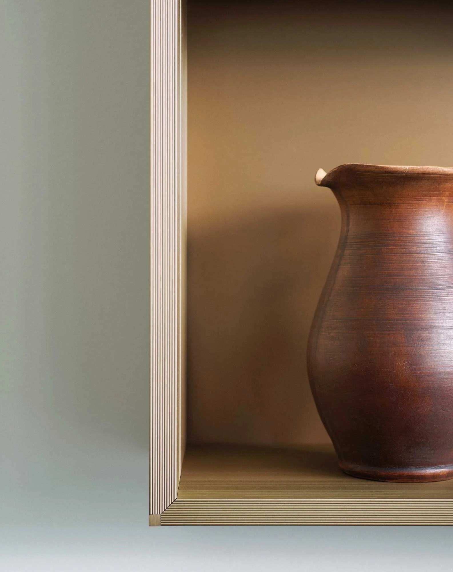 Ein rechteckiges Holzregal mit einer großen, braunen Vase auf der rechten Seite, das Regal hat eine graue Wand im Hintergrund.