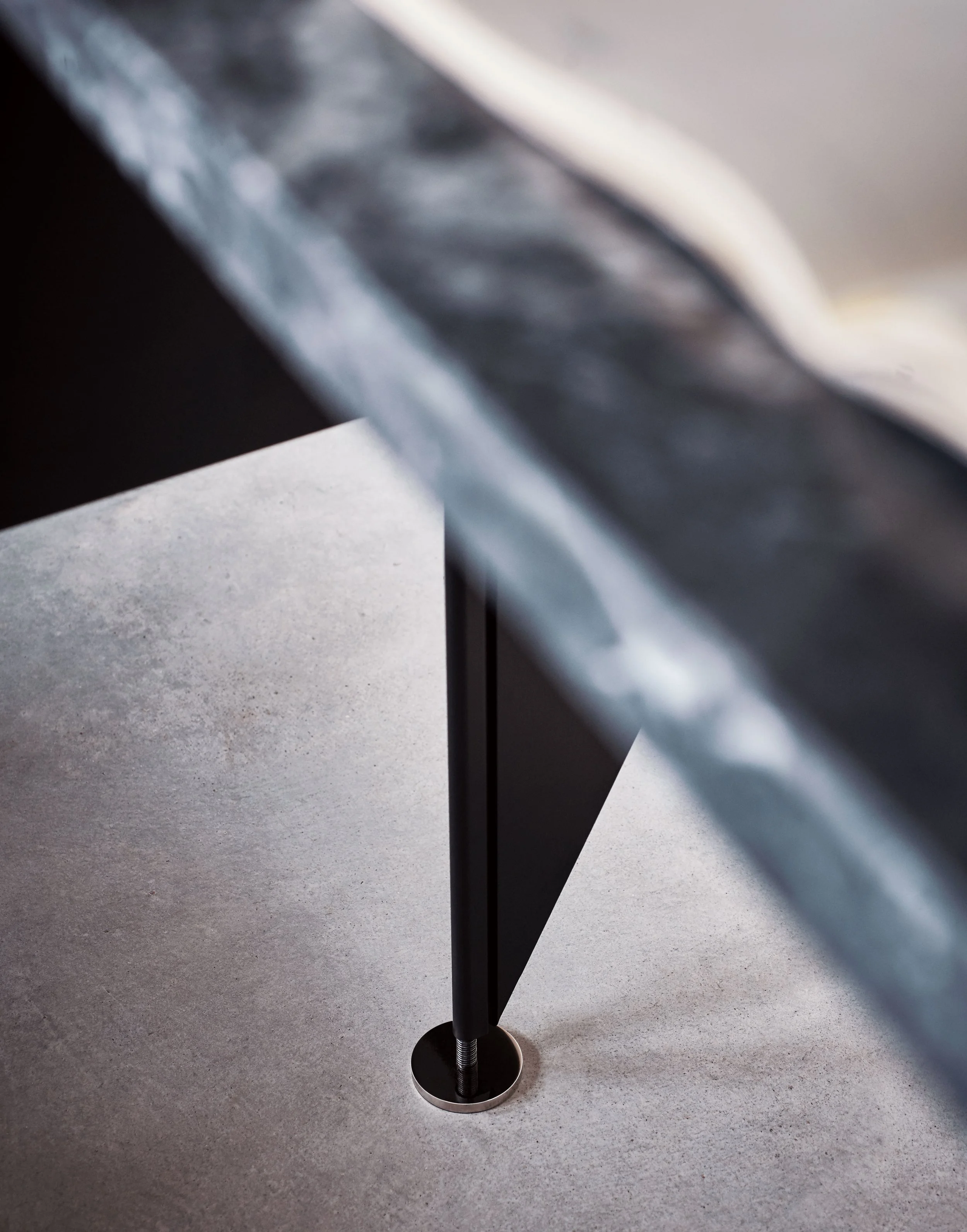 Nahaufnahme eines Metallständers mit runder Basis auf einem grauen Boden.