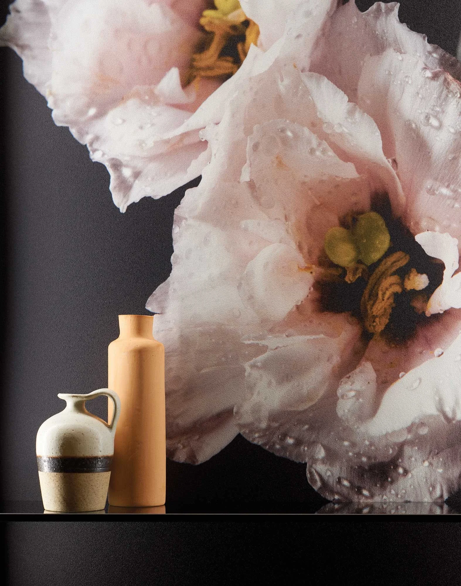 Nahaufnahme eines rosa, harzartigen Gesteins mit glatten und rauen Oberflächen, Wasserringen und einem kleinen grünen Schein