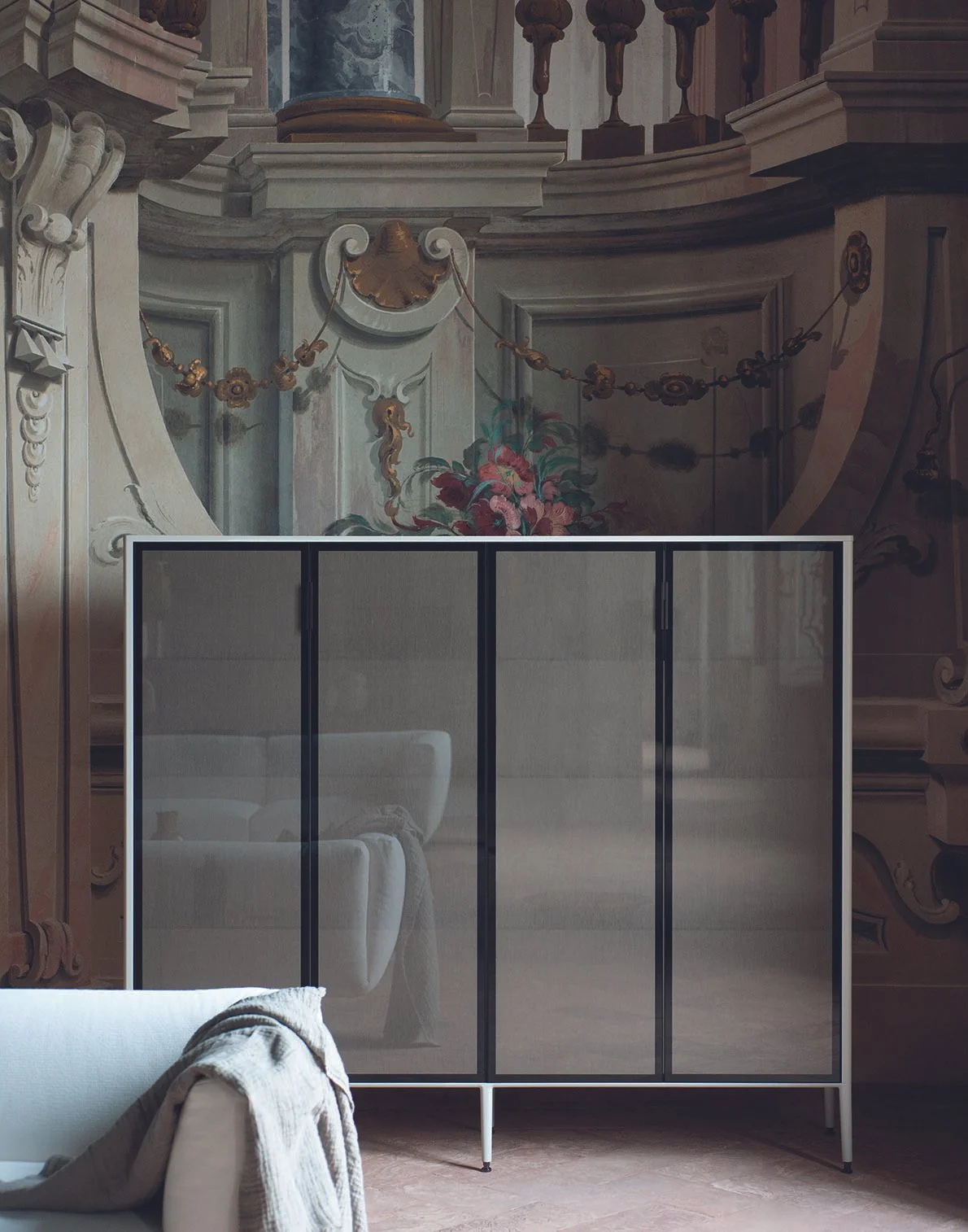 Moderner Rostfleckenbildschirm in einem Raum mit traditionellen Wanddekorationen im Hintergrund, im Vordergrund ein Sofa mit einem Tuch