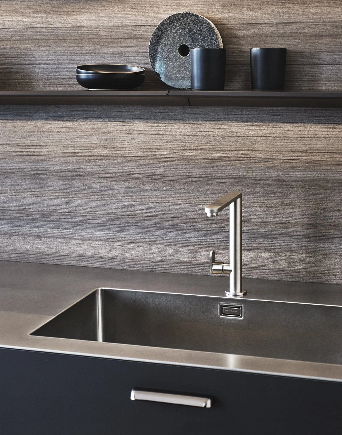 Moderne Küchenspüle mit Wasserhahn vor Holzwand, Dekorationsschalen und -utensilien auf der Regalebene