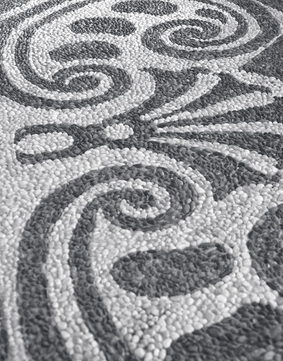 Mosaik aus kleinen schwarzen und weißen Steinen, die ein Mustern und Text bilden.