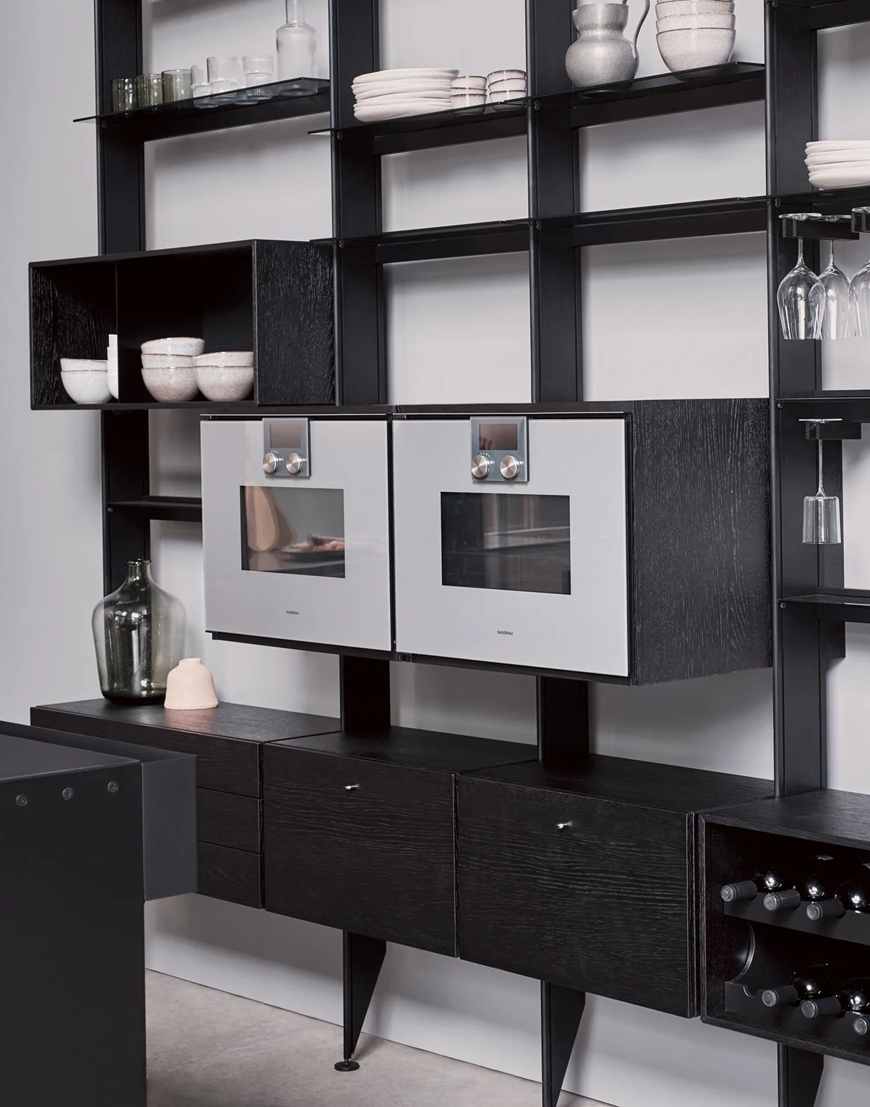 Moderne Küche mit schwarzen Regalen, weißen Backöfen, Gläsern, Geschirr und Dekorationen