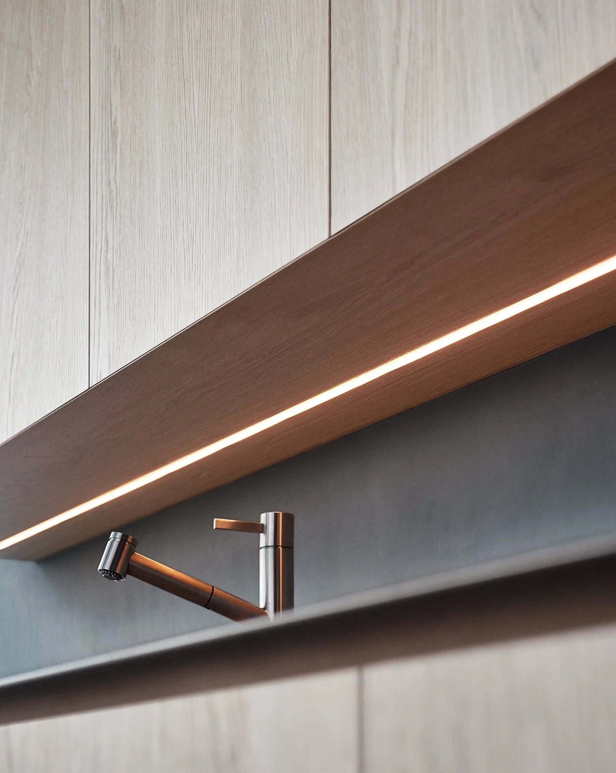 Moderner Wasserhahn über einer Spüle, flankiert von einer Holzdecke mit LED-Beleuchtung.