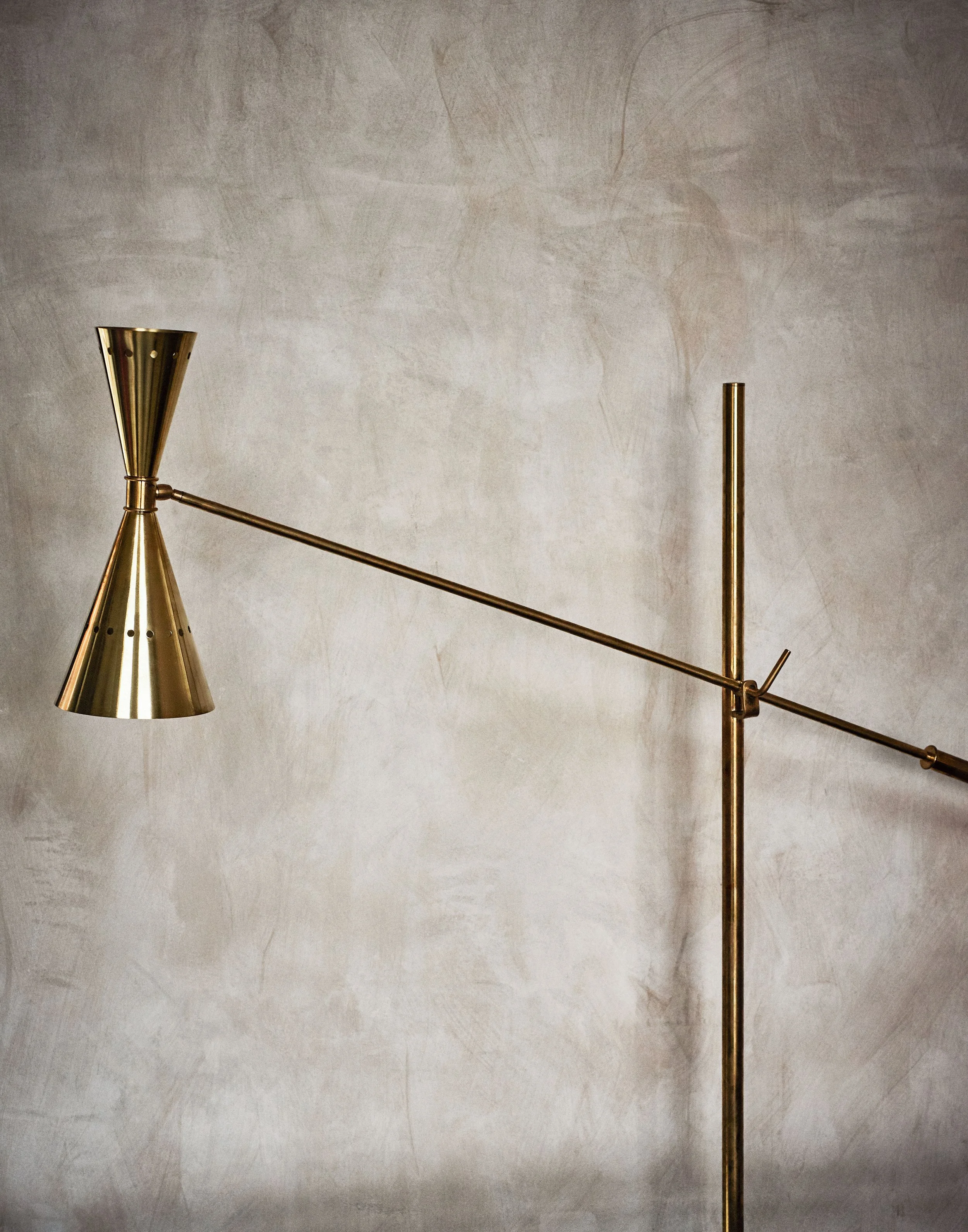 Moderner Steh-Lampenschirm in Goldfarbe auf einem mit Goldfarbenem Stativ und Stange, vor einer hellen Wand.