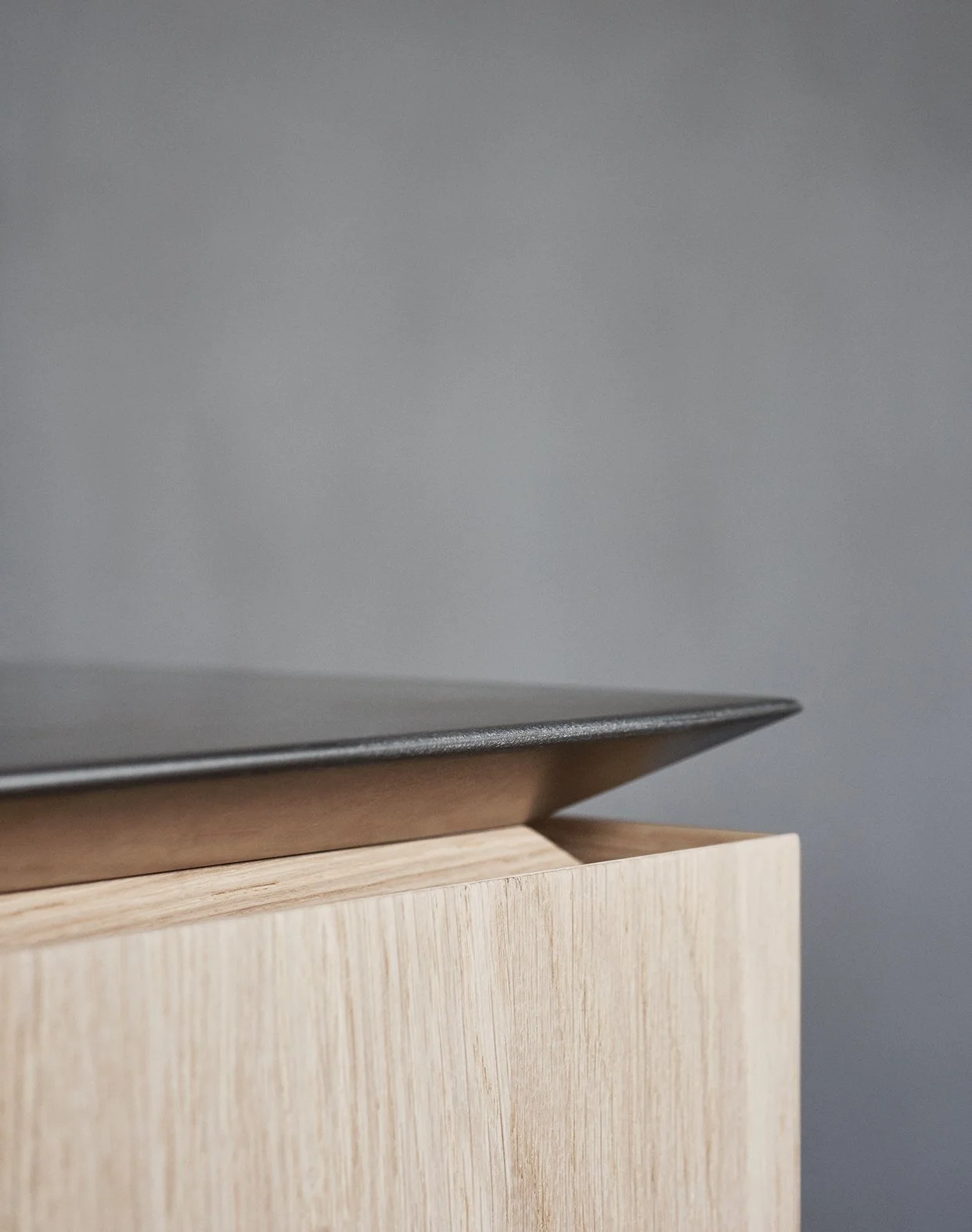 Nahaufnahme eines Laptops auf einem Holztisch vor einer grauen Wand.