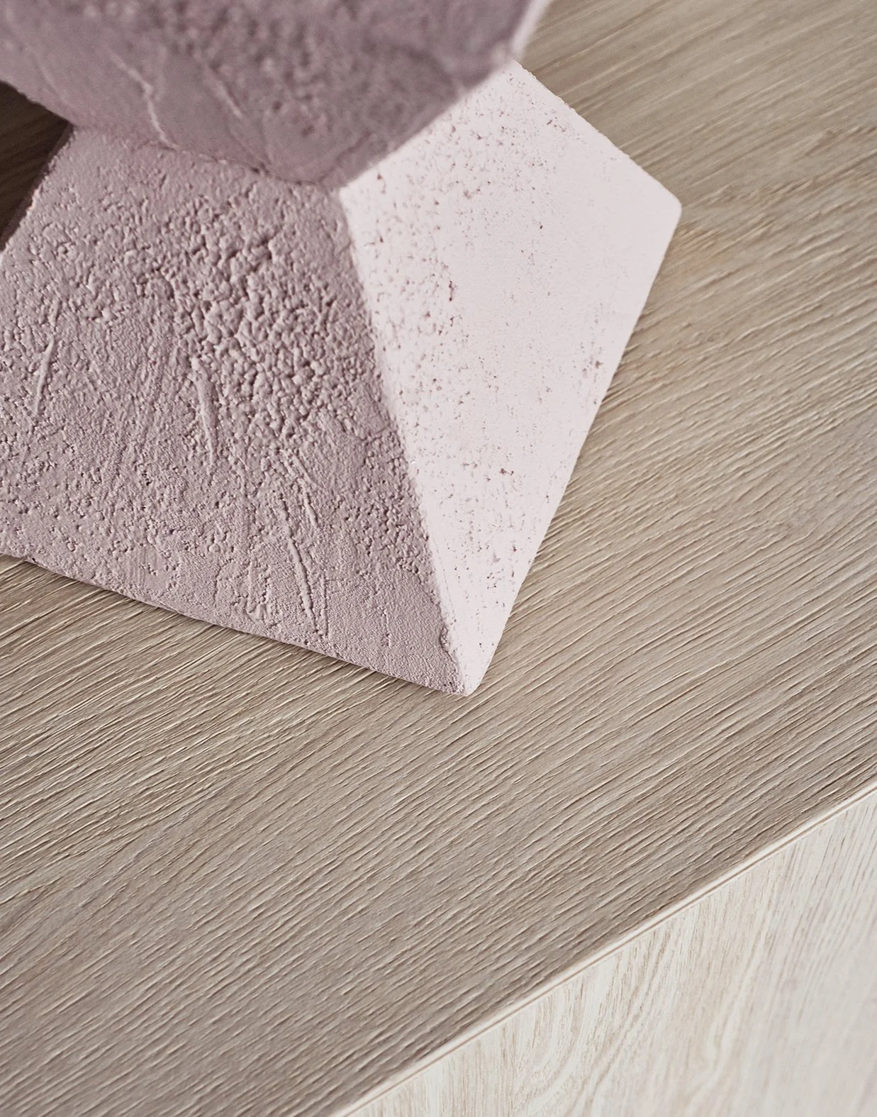 Nahaufnahme eines rosa Pyramidenförmigen Gegenstands mit strukturierter Oberfläche auf einem holzfarbenen Tisch.