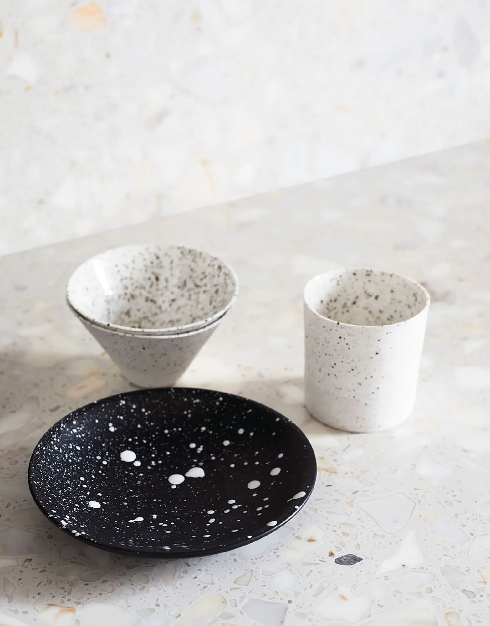 Schwarzer und weiße Speckstein-Tabletts und -Schalen mit weißen Flecken, auf einem weißen, steinartigen Tisch.