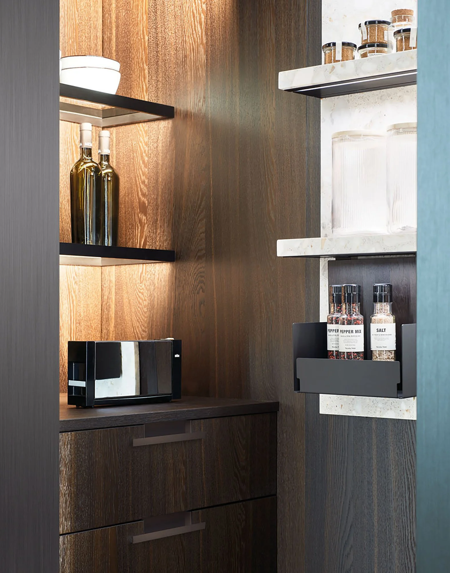 Ein Einbauschrank mit offenen Regalen, gefüllt mit Küchenartikeln wie Pfeffer- und Salzstreuern, Glaswaren und Gewürzgläsern aus Holz und Glas.