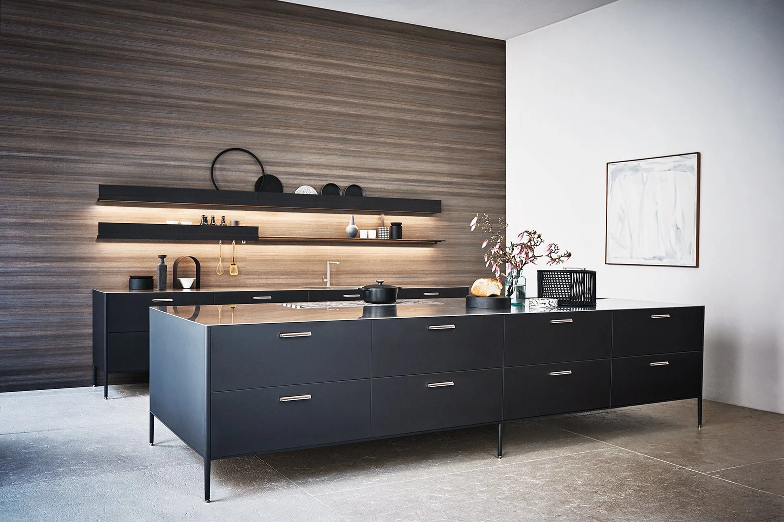 Moderne schwarze Küchenschränke mit offenen Regalen und stilvollen Dekorationselementen an einer eleganten Holzwand. Das minimalistische Küchendesign kombiniert funktionale Aufbewahrung mit ästhetischer Präsentation und schafft eine hochwertige, mode